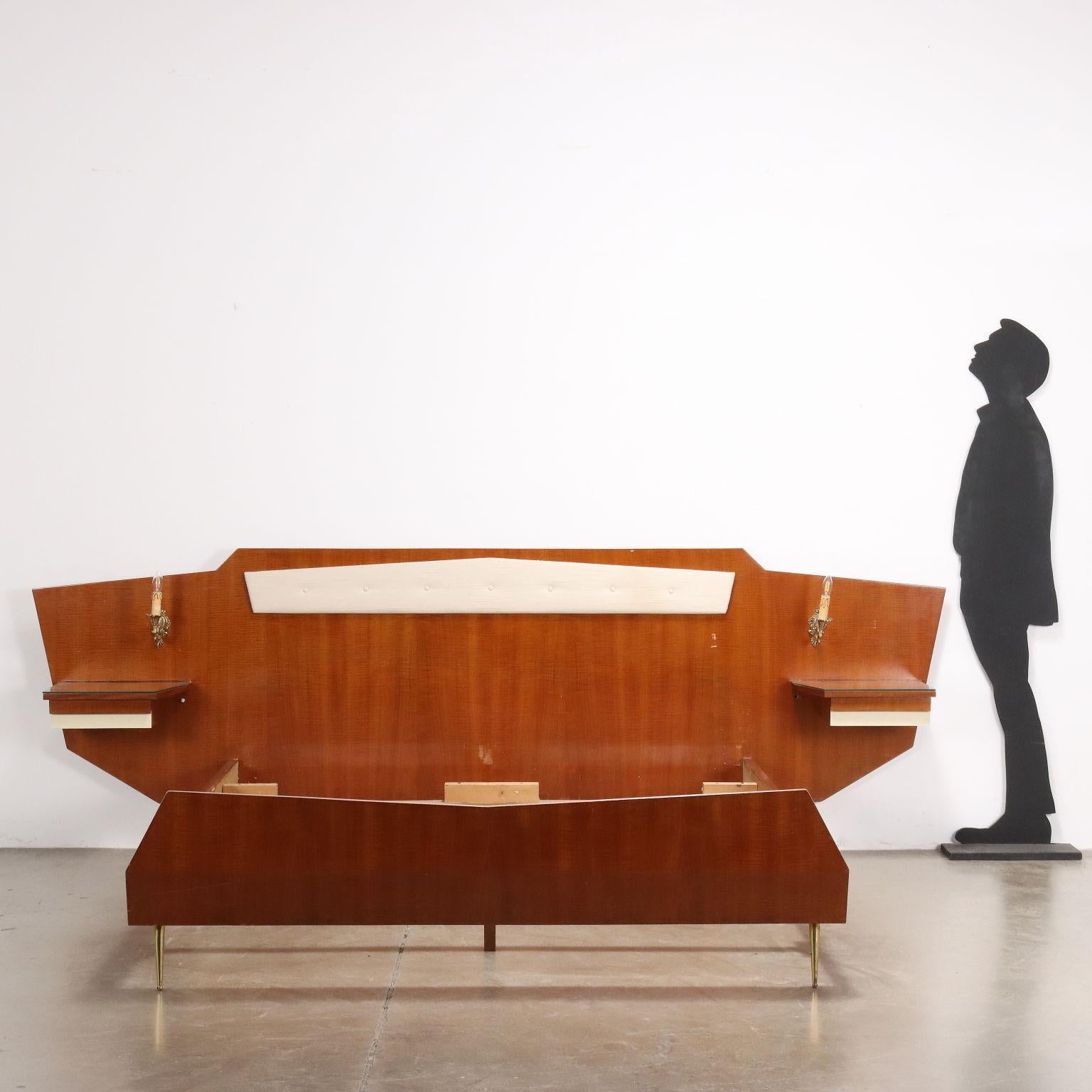 Bett mit hängenden Nachttischen mit Schublade, Kopfteil mit Schaumstoffpolsterung und Stoffbezug, Mahagonifurnier, Formica-Einsätze, Messingbeine, ein Paar Wandleuchten aus Messing. 