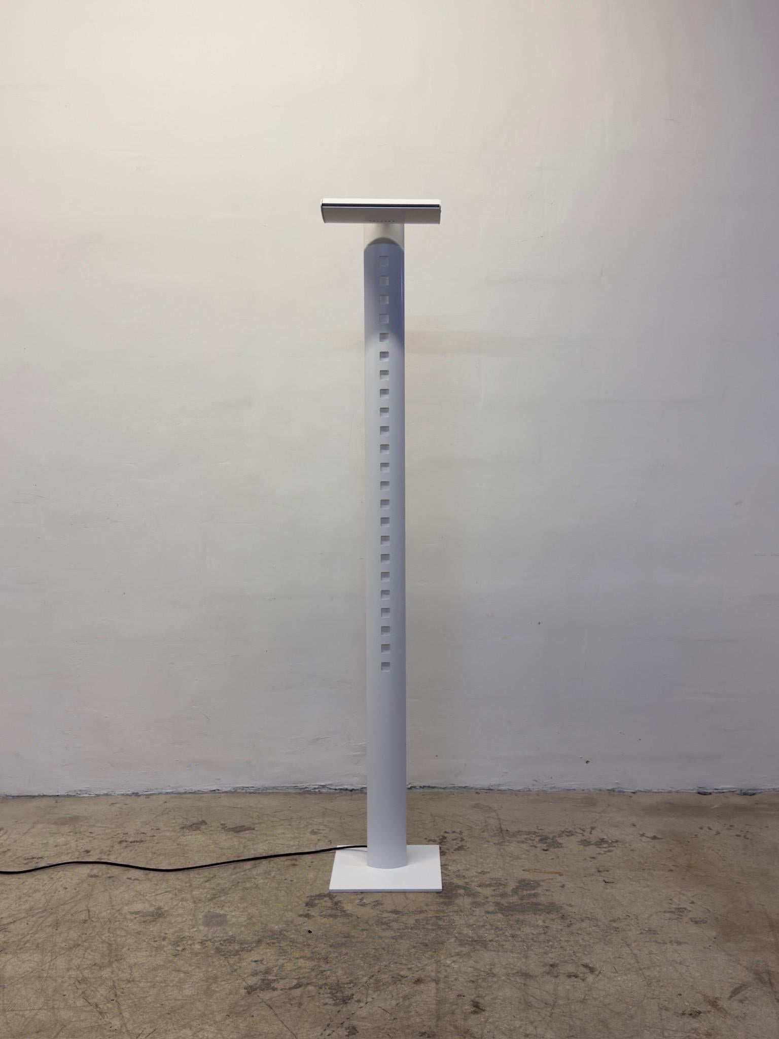 Postmodern white torchiere floor lamp with a fluorescente inner tube bulb that illuminates both the perforated front and the back through ribbed Perspex.  The top torchiere consists of a halogen bulb that is dimmable using a touch sensor and the