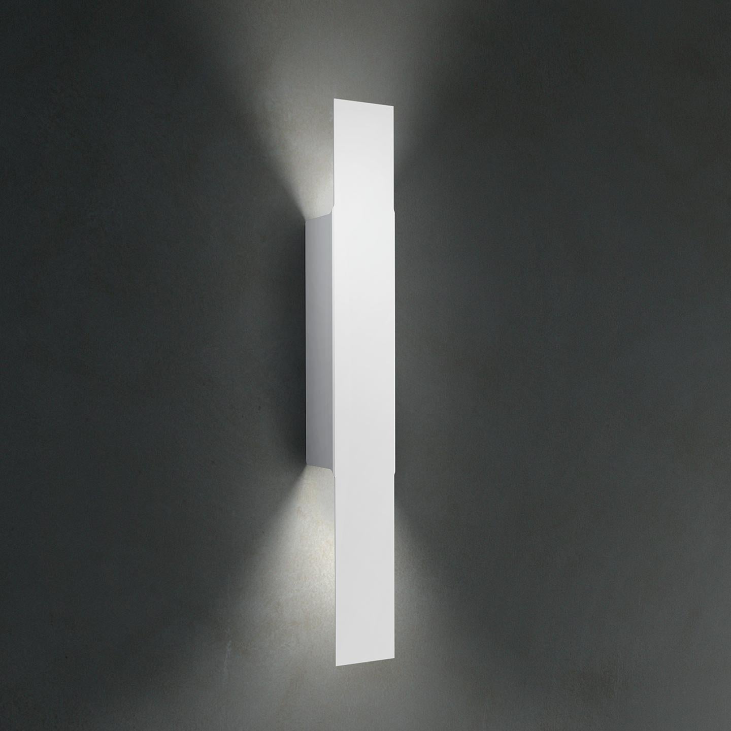 Opi is a sleek and architectural wall lamp made of metal twisted to create a compelling, asymmetric diffuser. It was designed in 2011 by Alessandro Piva to be a minimal yet effective wall lamp that is applicable to many contract or residential