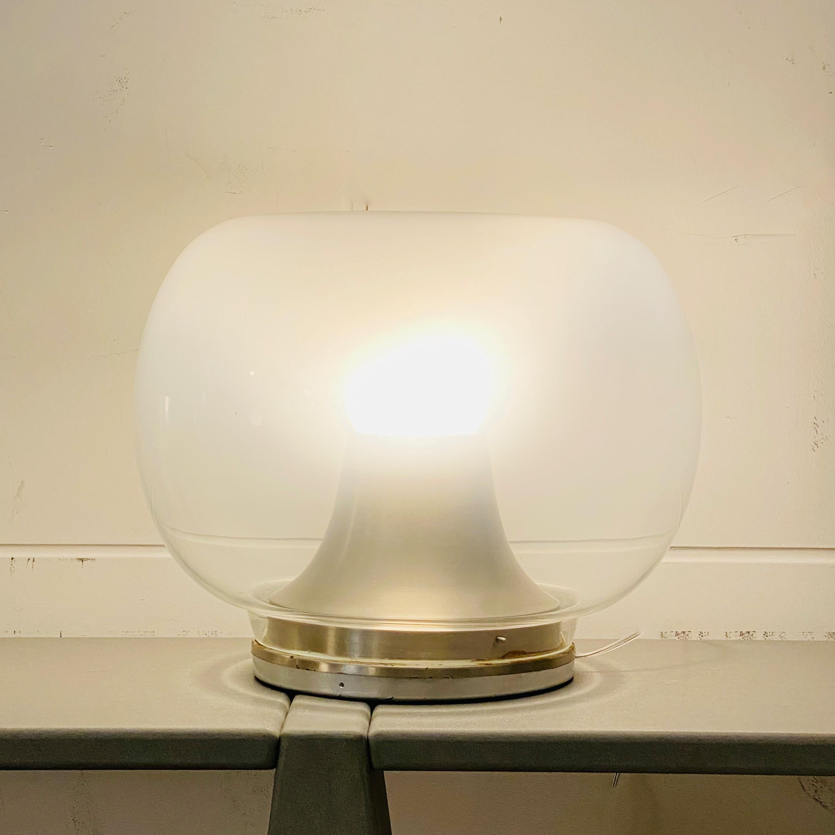 The style of this large table lamp is reminiscent of the lamps produced by Leucos in the 1970s. The diffuser of the lamp is made of opaline glass shaded in shades of white, concave at the top. The lamp has a light point and the internal lamp holder