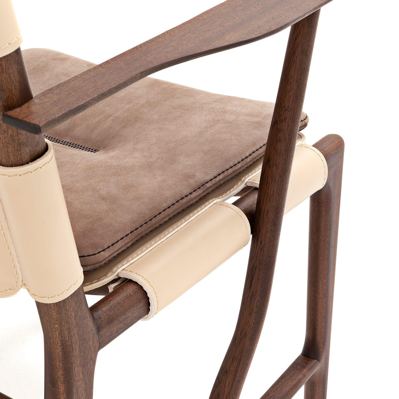 First-rate materials such as saddle leather, mahogany and precious textiles merge in this superb chair with armrests that draws inspiration from nature and tree branches. The backrest is covered with beige saddle leather, while the seat features a