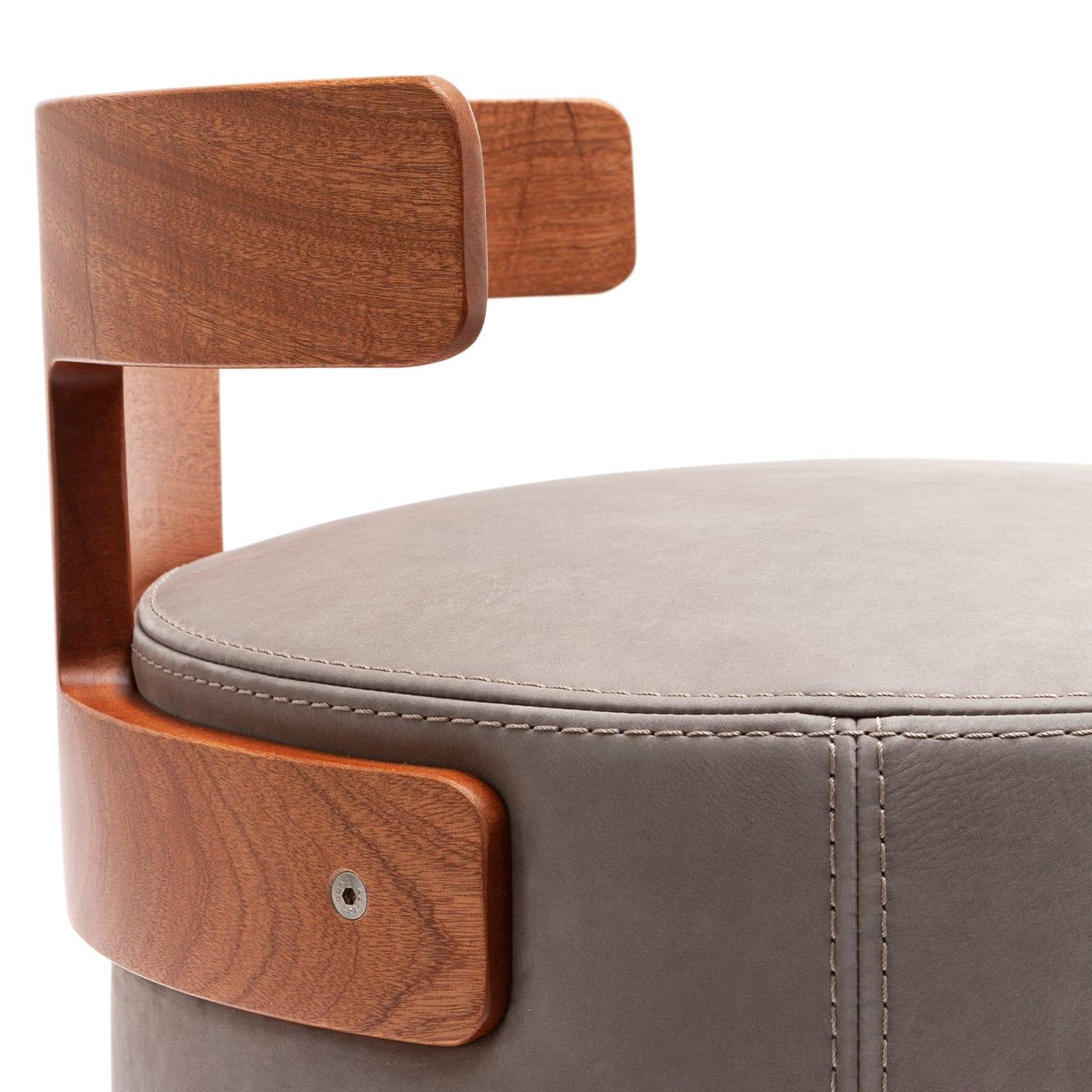Personnalisable et de caractère singulier, ce pouf est un design raffiné et ergonomique de Massimo Castagna. Doucement rembourrée, l'assise cylindrique est revêtue de cuir Nabuk beige et est soutenue par un dossier en forme de T en acajou. Il est