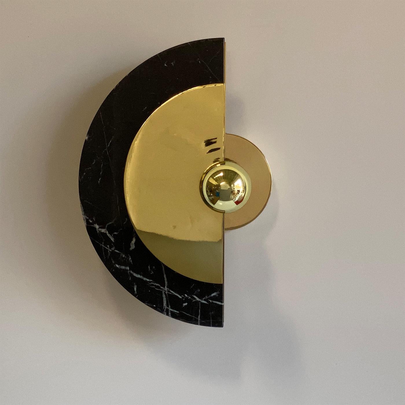 Part of the signature Levante Collection, this impressive wall sconce is fashioned of prized black Marquina marble and elegant polished brass. It features two half disks of these stunning materials which may be rotated 30° on the central sconce arm