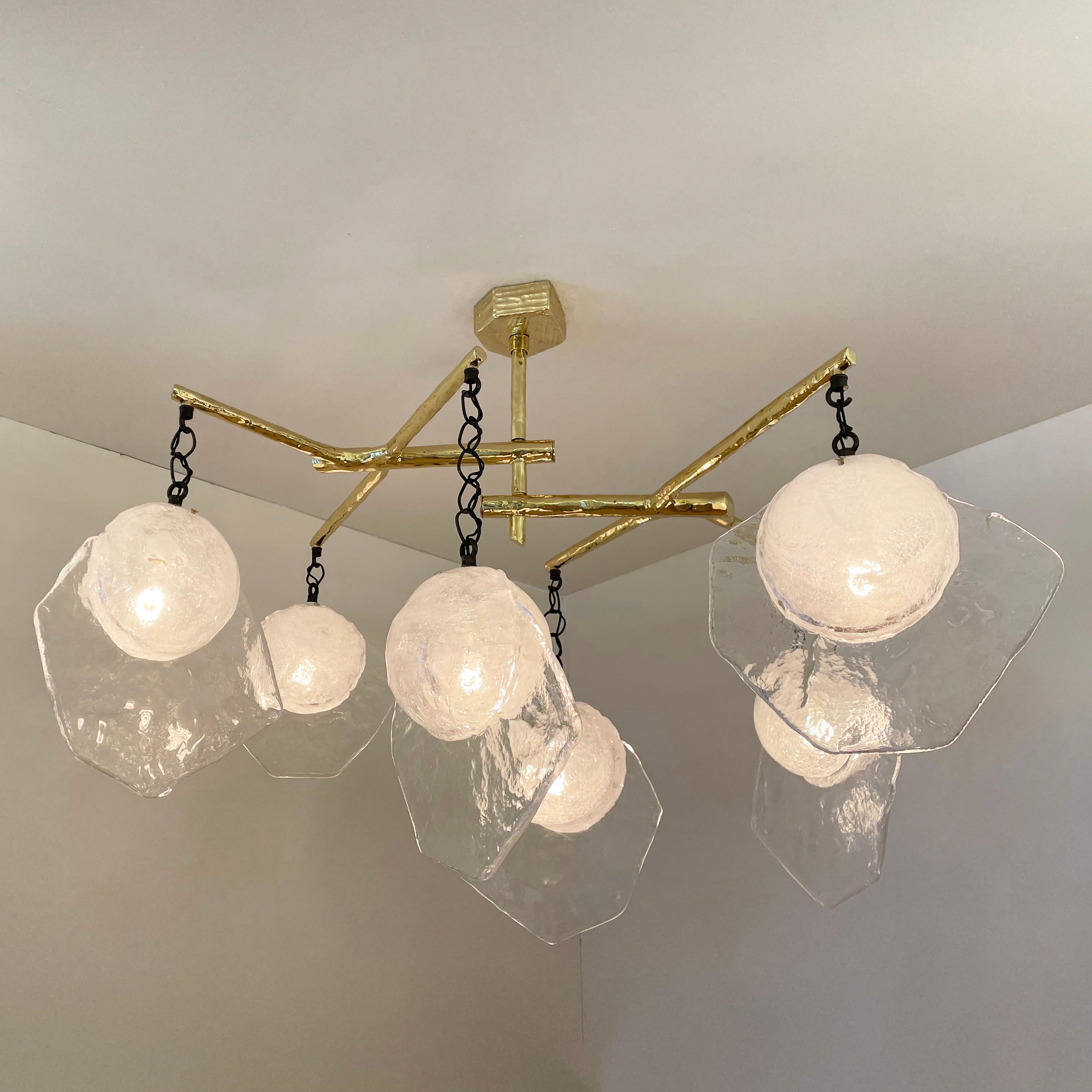 The Levante ceiling light is composed of six Murano glass elements hanging from an organic cast brass frame. Each hand blown glass has a bubble infused core and a textured fin. Shown with a polished brass frame and Brunito Nero