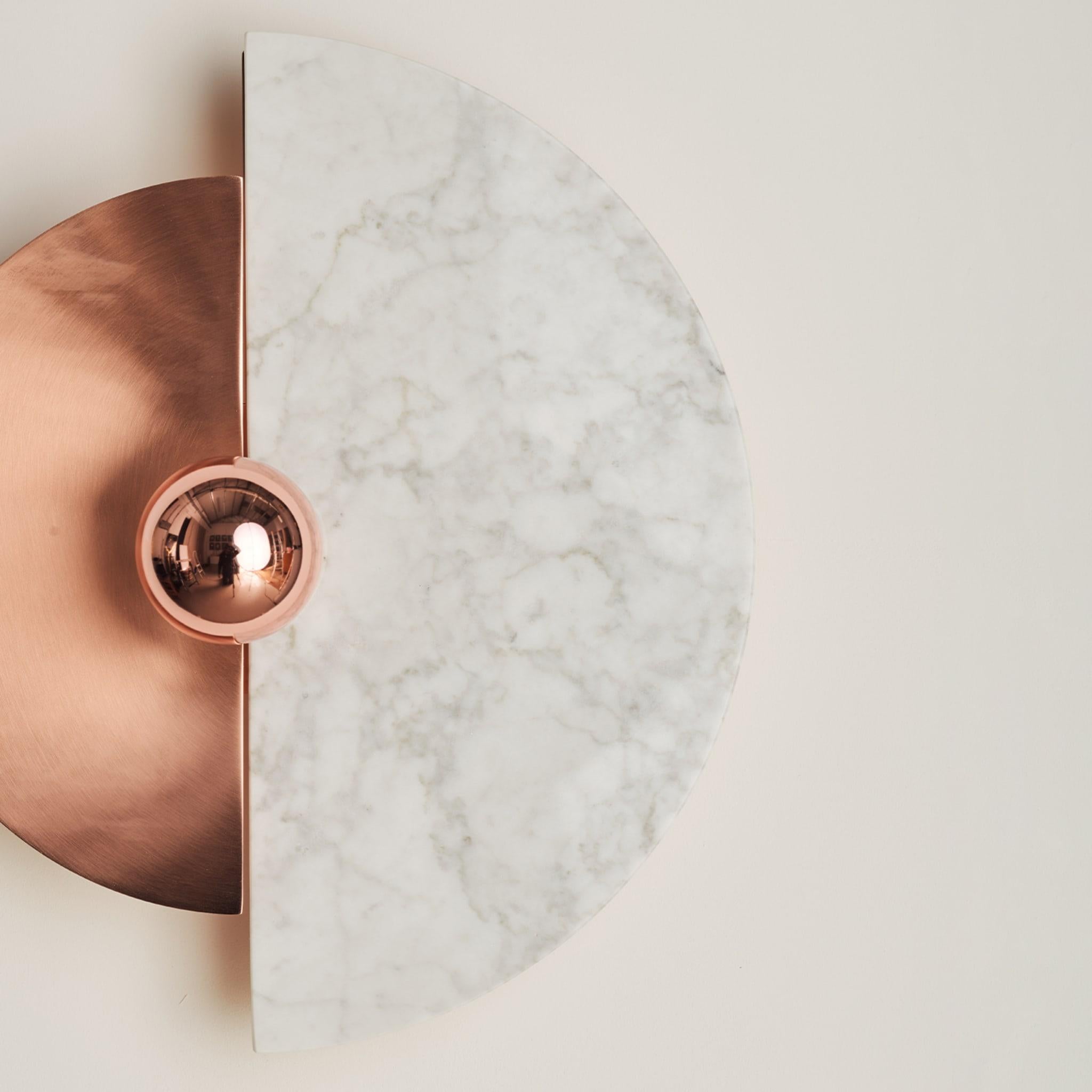 The Levante wall sconce, with its circular shape, evokes the sun. The ability to position the discs in 12 different ways creates unique interplays of light and shadow on the wall. The brass structure and disc, along with the marble disc, are