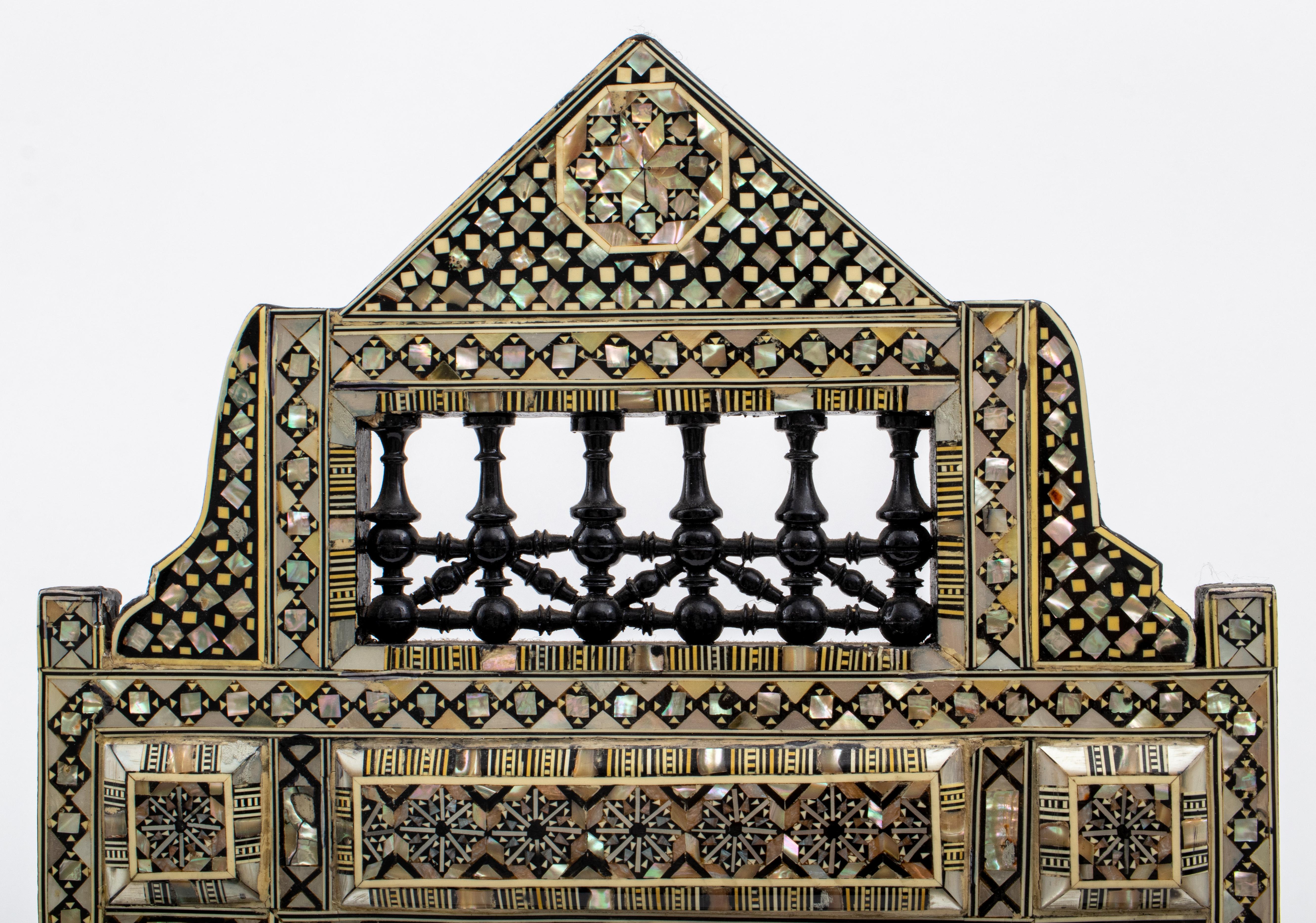 Levantine mother-of-pearl & ebony marquetry mirror, with triangular openwork pediment with turned fretwork, the whole veneered with applied geometric marquetry decoration, centering a beveled rectangular mirror. 
Measures: 20.5
