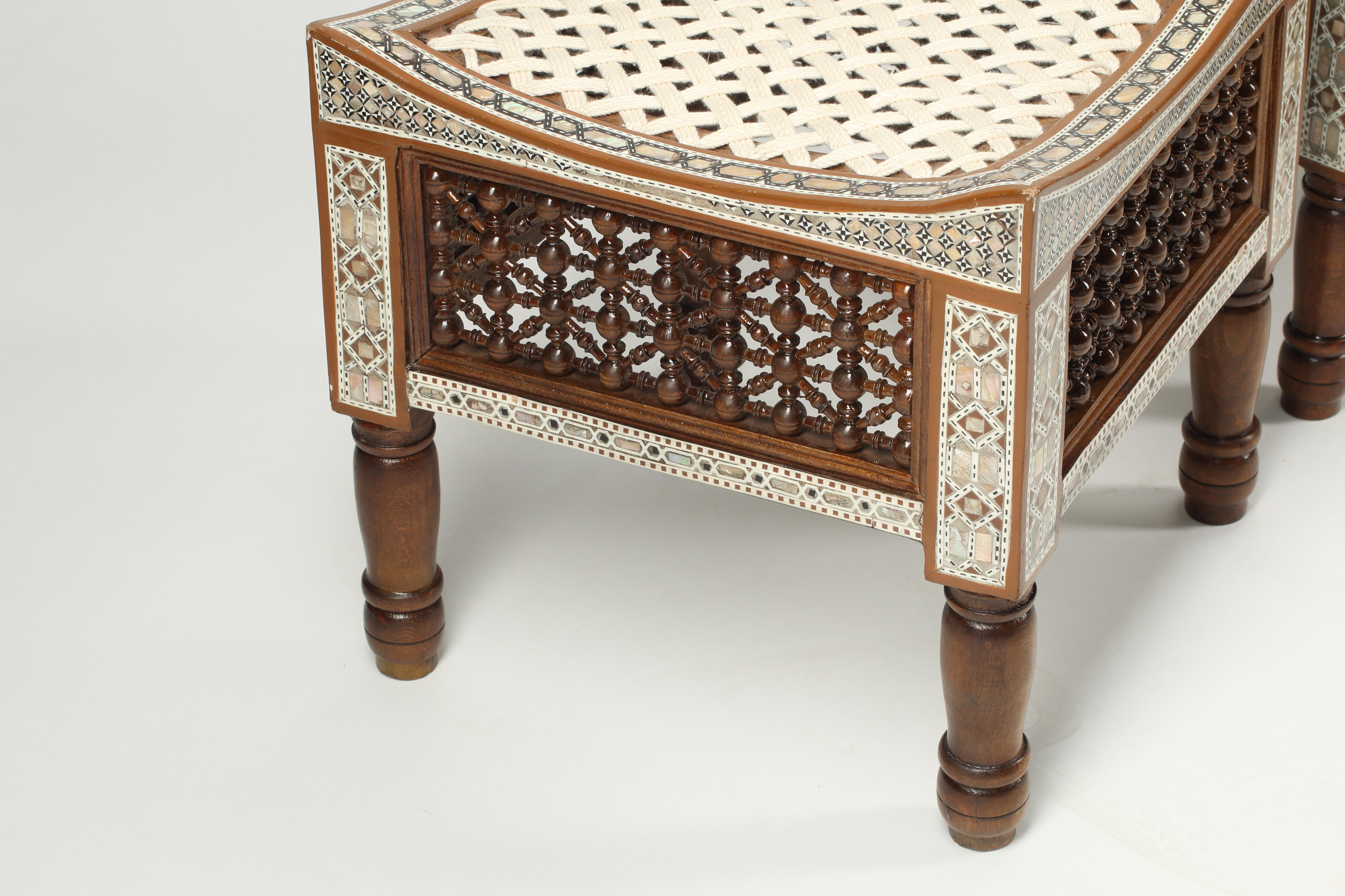 A set of four levantine mother of pearl inlay stools with carved wooden sides and legs. Curved seat frame on four turned legs united by stretchers, with interlaced rope seat.