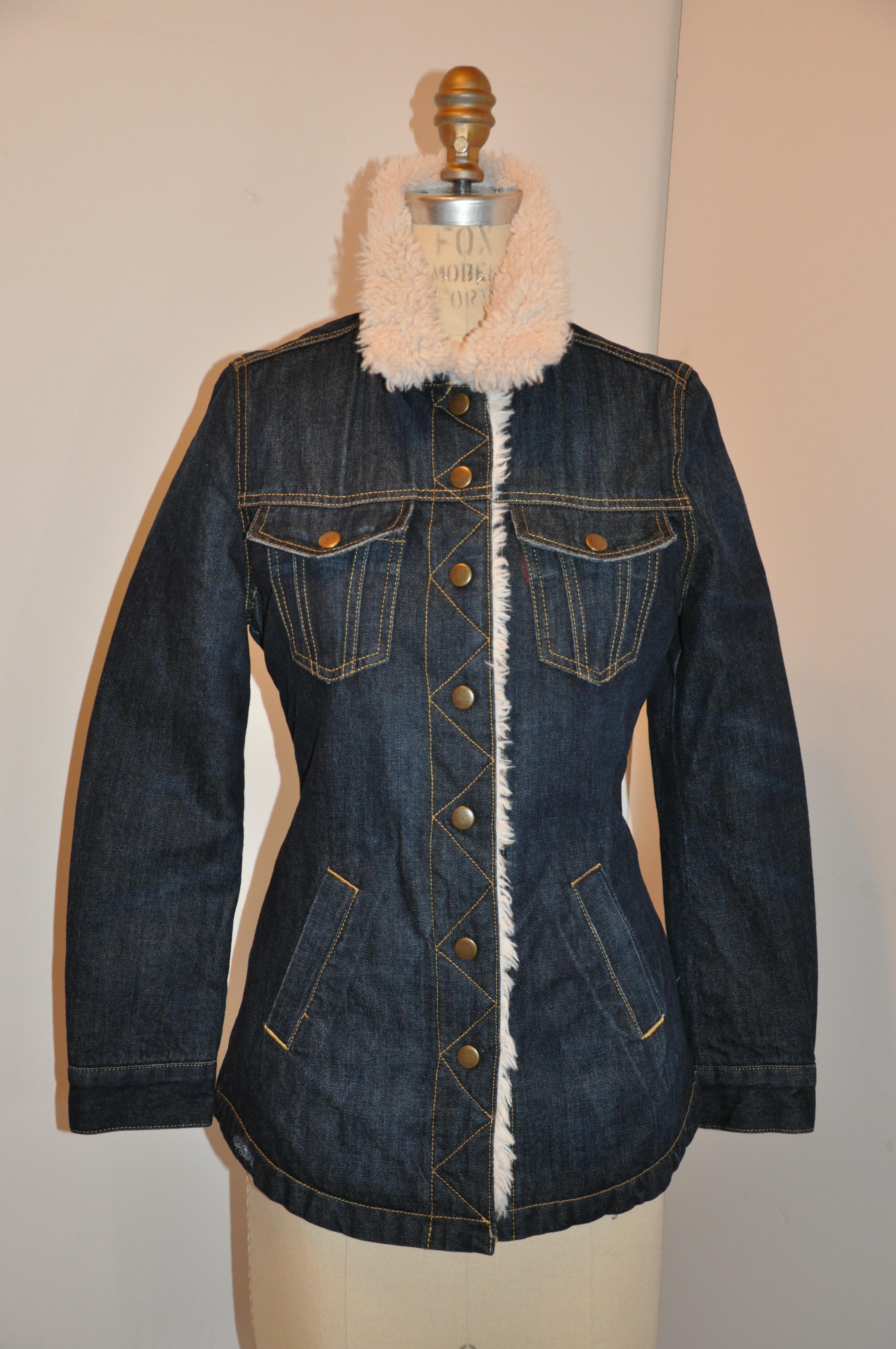 Levi faux fur-lined distressed navy denim snap-front collar with scallop hemline jacket has 7 snap closure in front accented with two patch pockets as well as two set-in pockets in front. Detailed top-stitching throughout. Shoulders measures 15