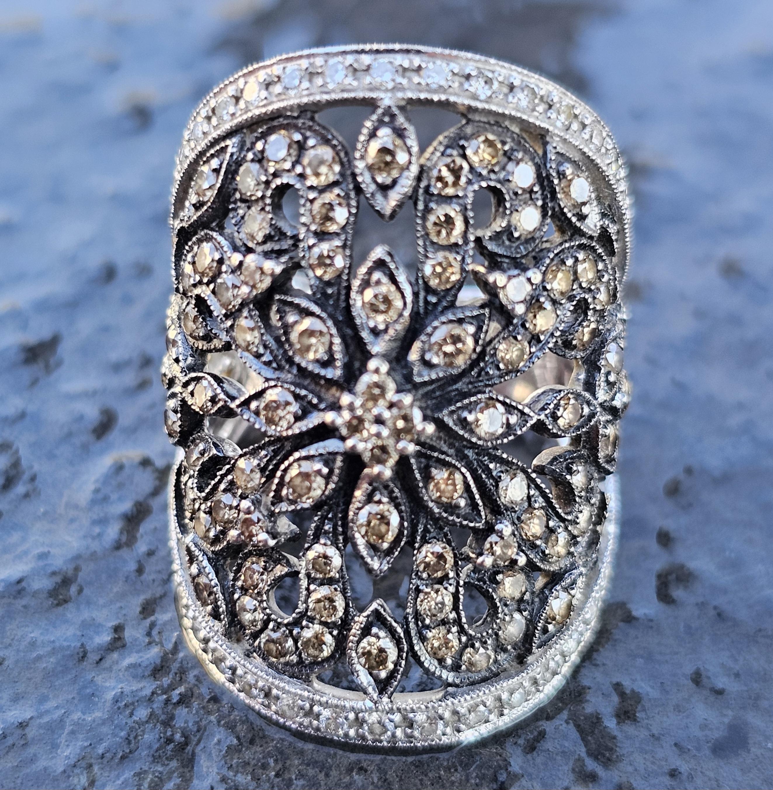 This exquisite band ring by Levian is a captivating addition to any jewelry collection. Crafted in 14k white gold, the ring features an intricate openwork design adorned with round brown diamonds. The diamonds are set in a floral pattern, creating a