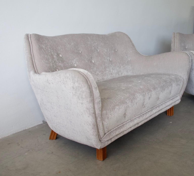 Two-seat button tufted sofa by Levy Carlson’s Möbelafärr from circa 1952. Newly upholstered in shiny light beige/grey velvet. Lightly curved back. Legs made of stained beech.