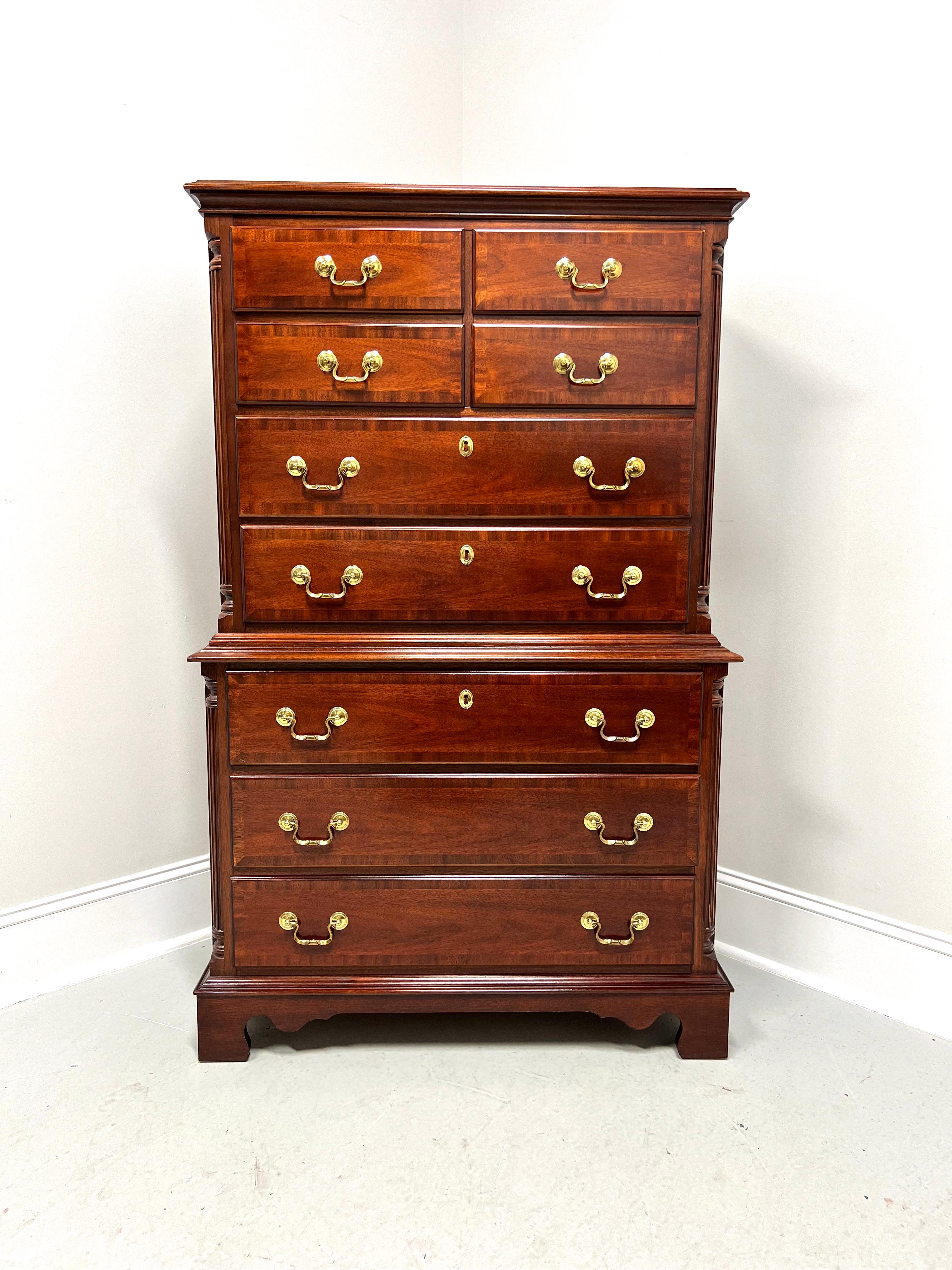A Chippendale style chest on chest of drawers by Lexington Furniture. Mahogany with brass hardware, banded top with an ogee edge, banded drawer fronts, decoratively carved columns to front sides, ogee edge dividing chests, and bracket feet. Features