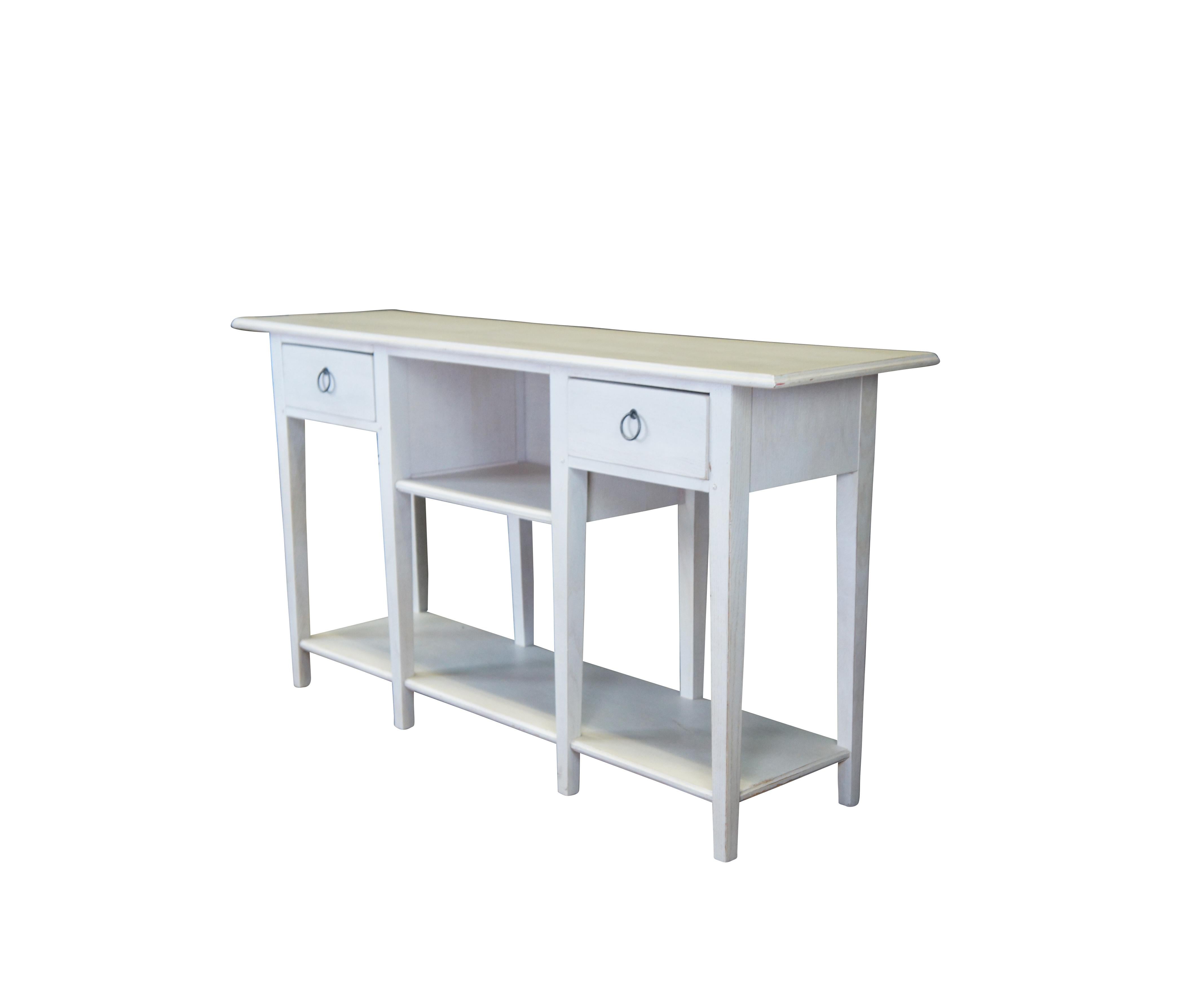 Lexington Furniture console or sofa table. Made from oak with a white painted finish. Features a rectangular top over a central cubby flanked by two dovetailed drawers, long tapered legs and lower shelf for accessory storage. Includes metal knocker