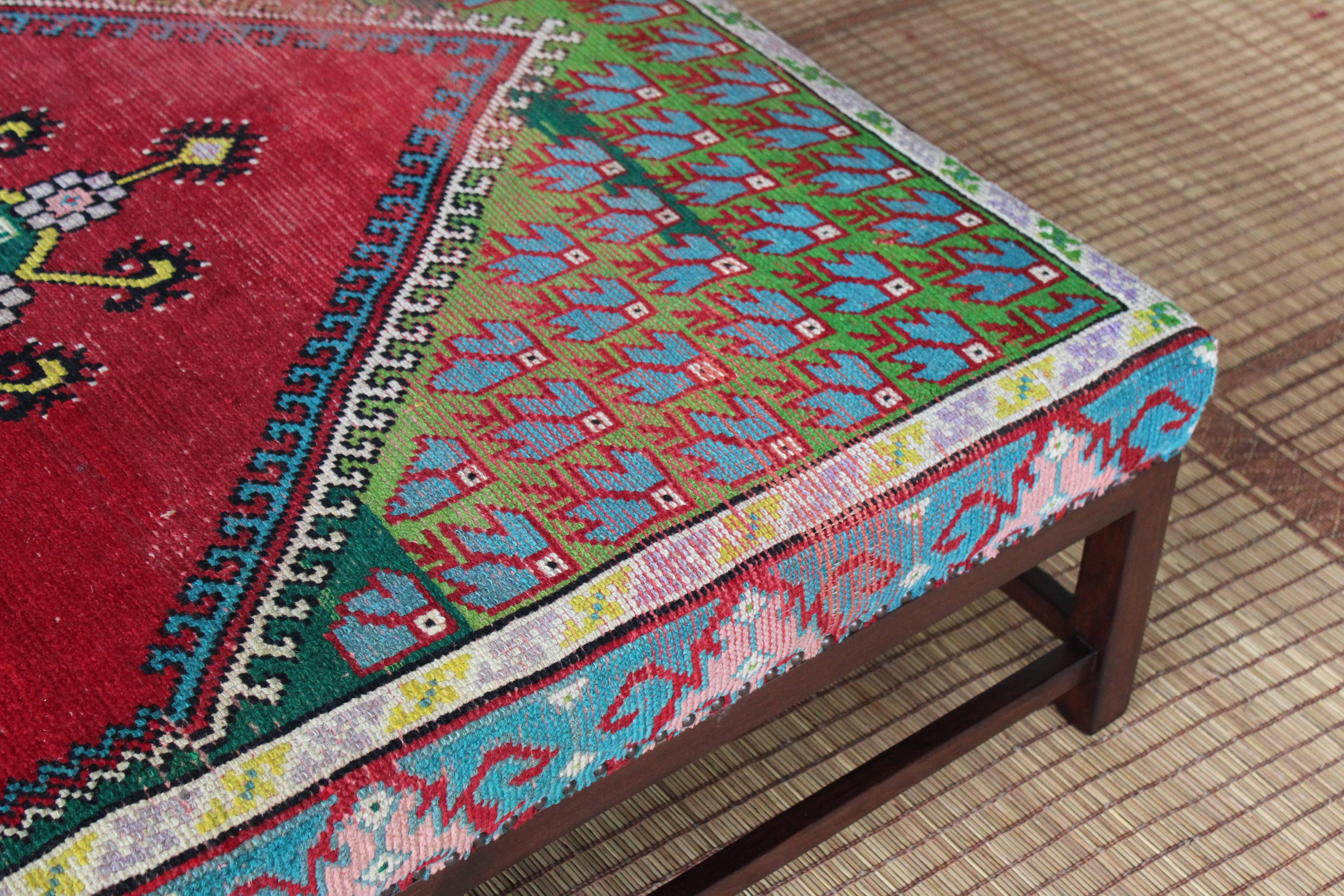 Custom-made Lexington ottoman by Hollywood at Home. Features a walnut base and upholstered in a vibrant vintage rug.