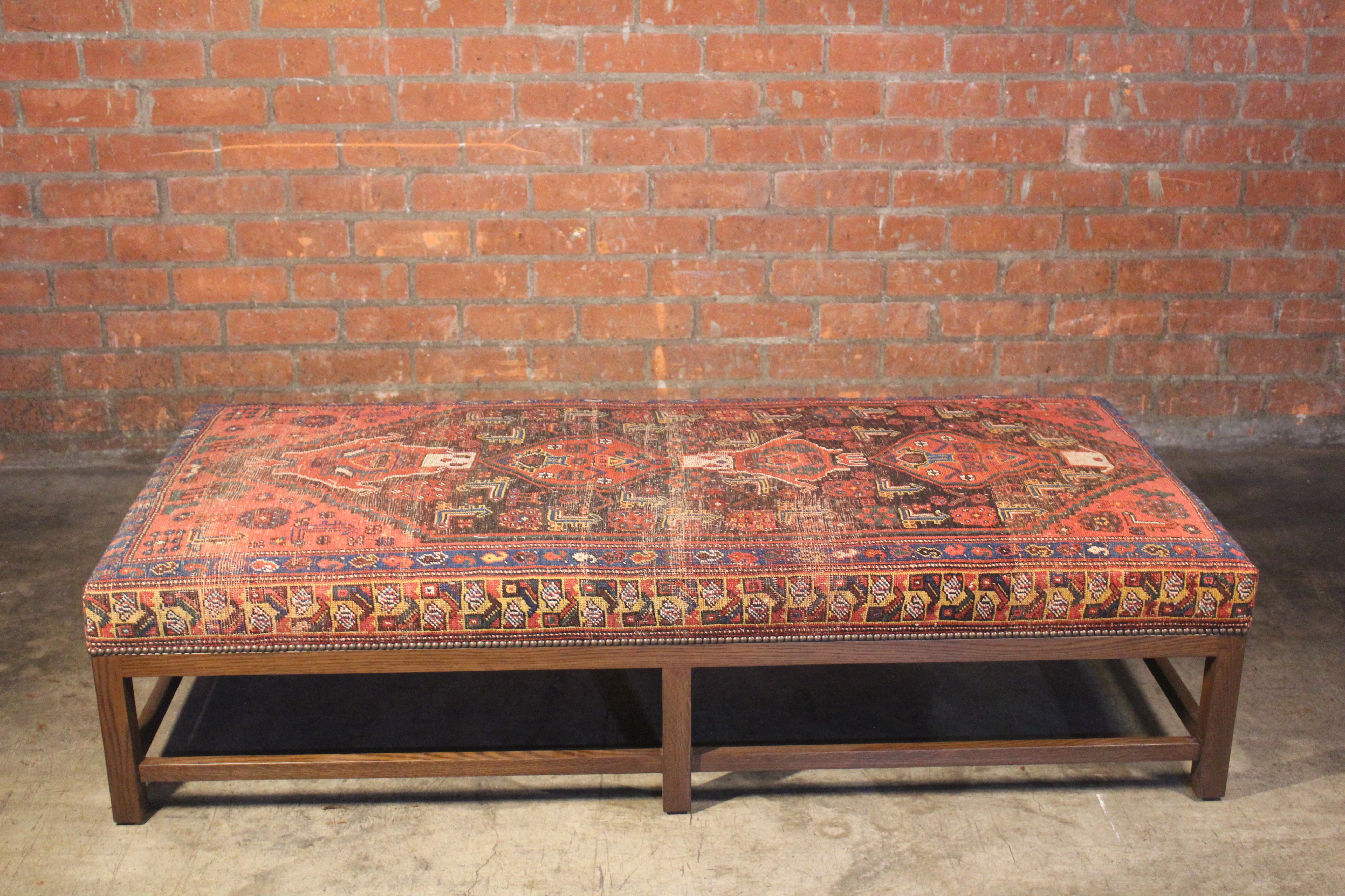 A custom-made Lexington ottoman upholstered in a vintage Turkish rug. Handmade in Los Angeles. The base is solid oak in a dark finish with antique brass nail heads. The rug has been professionally cleaned prior to upholstery.