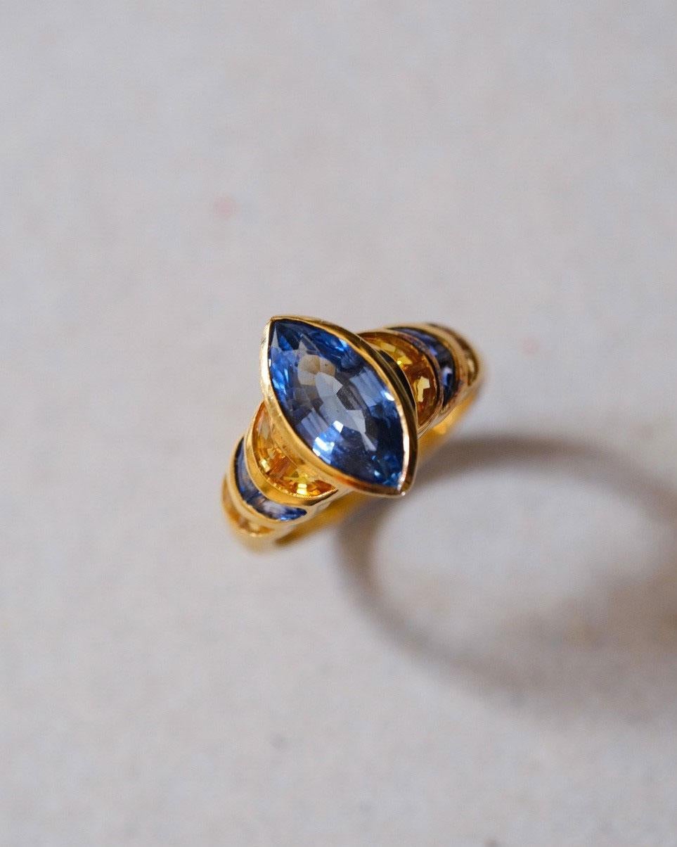 Bague LEYSER en or jaune 18 carats (7,45 g), sertie de :

1x saphir bleu (fac., taille navette, 4,11ct)

4x Saphir bleu (fac., taille fantaisie, 0.49ct)

8x Yello Sapphire (fac. fancy-cut, 0.95ct)