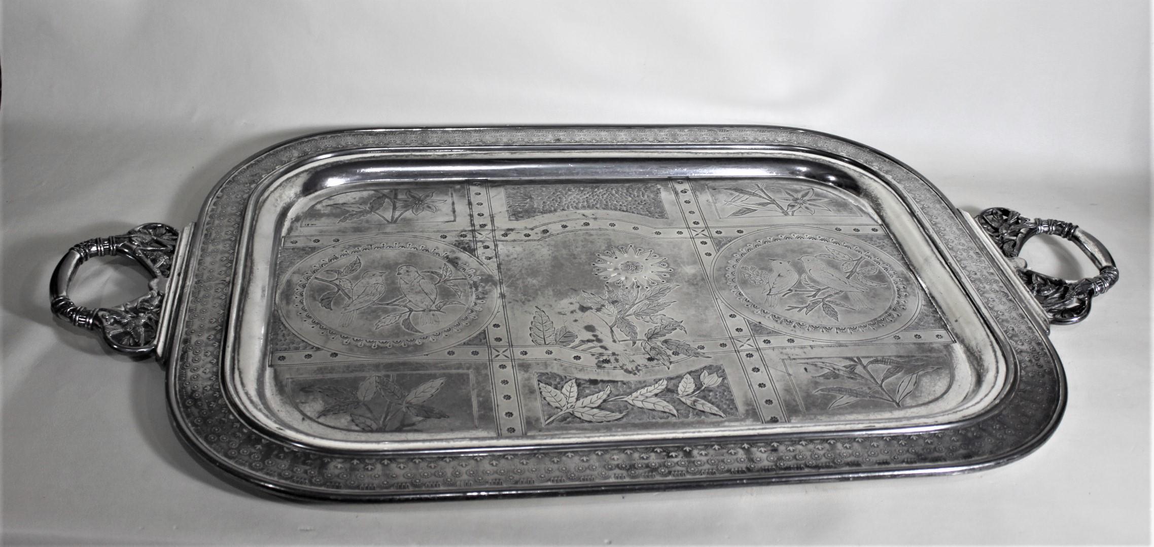 This very large and substantial silver plated serving tray is unsigned, but presumed to have been made in the United States in approximately 1900 in the period Aesthetic Movement style. The tray has a very ornate stylized floral border with ornate
