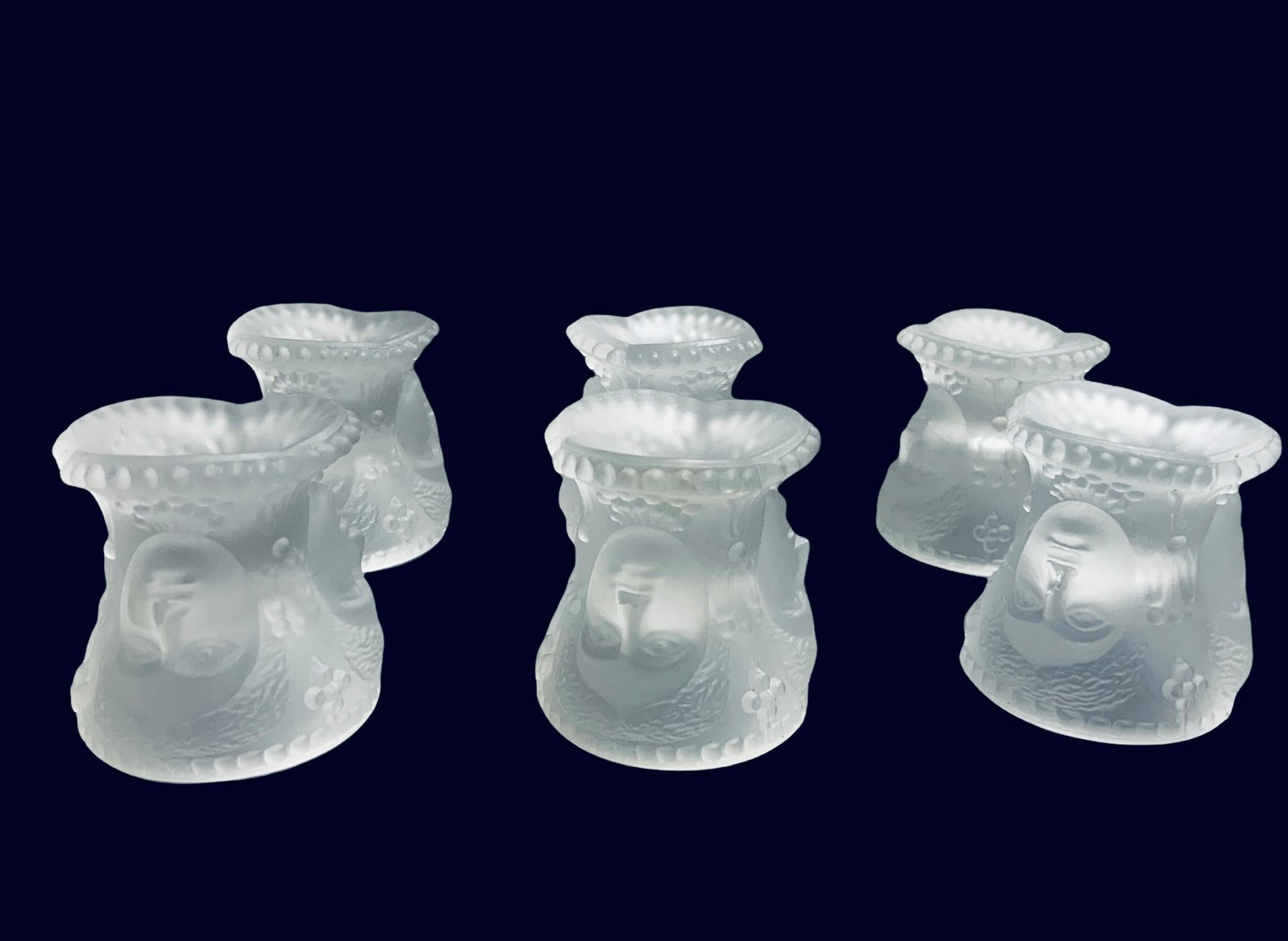 This a L.G. Wright Glass Co. Set of six frosted glass Three Faces Salt Cellars. They depict the same face three times of a woman/goddess whose head has a lot of wavy hair and is adorned with flowers at each side. It also appears that she has some