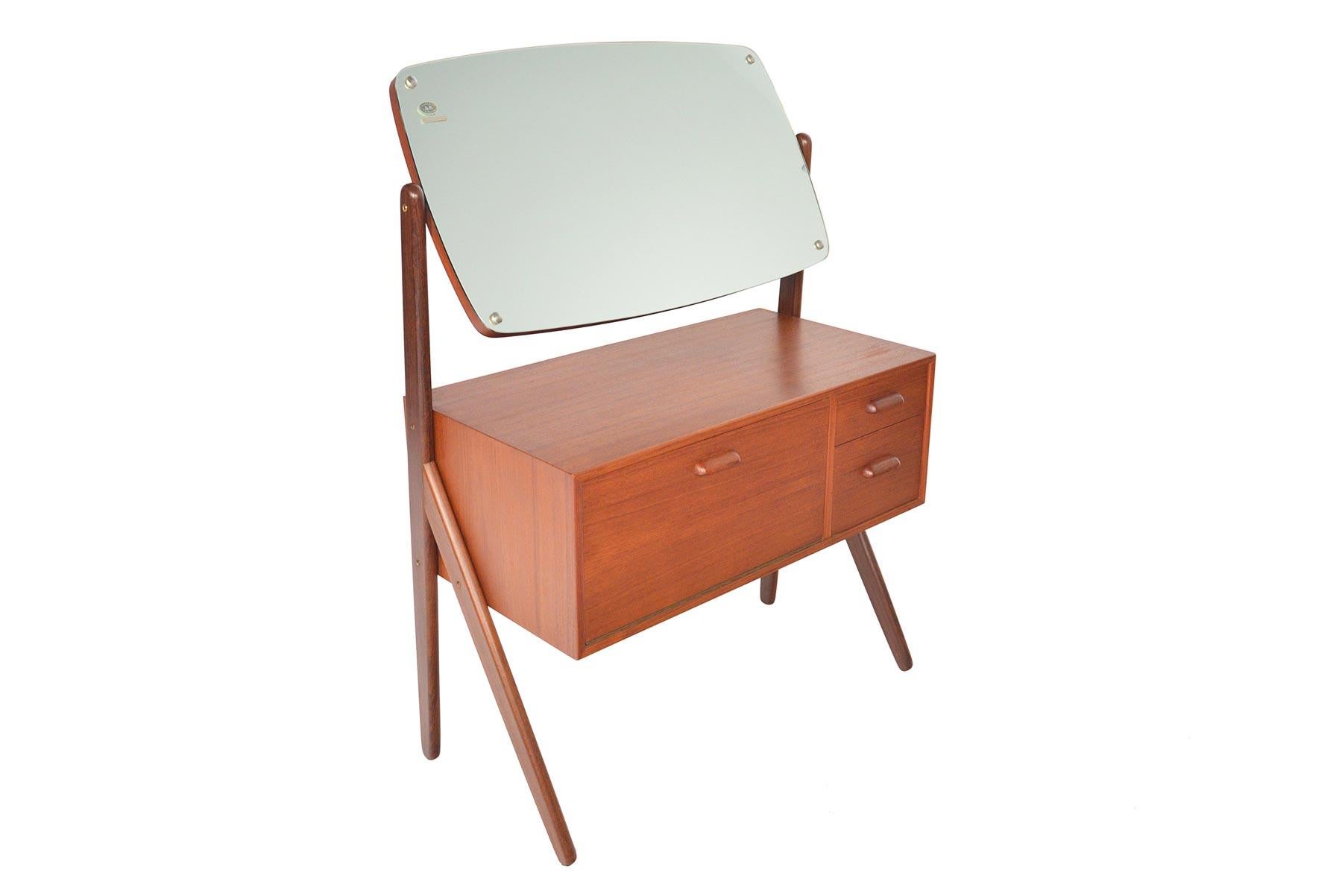 This gorgeous Danish modern teak V-legged vanity Model 593 by Ølholm Mobelfabrik offers wonderful lines in a small footprint! Featuring an articulating vanity mirror, this piece exceptional storage with two drawers and a laminate lined cubby. In