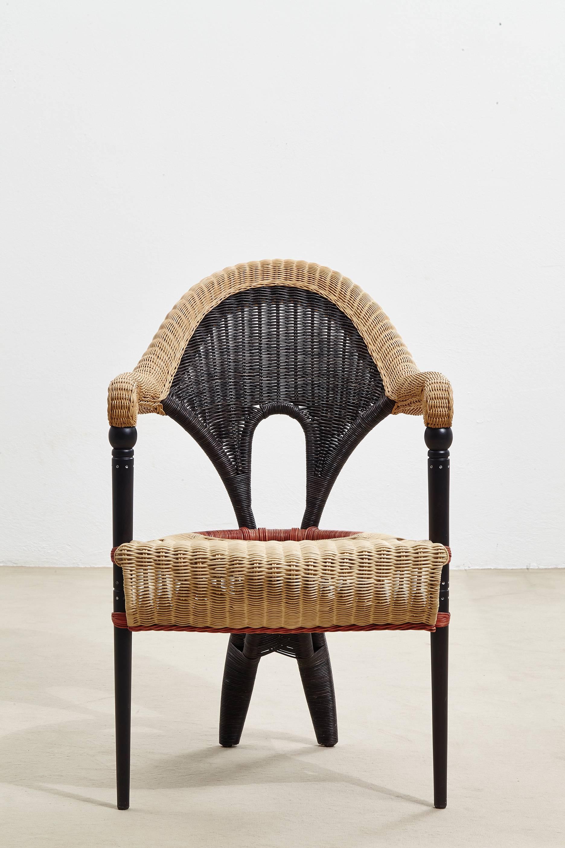 An elegant small armchair with sinuous lines designed by Borek Sipek for Driade. The organic form of the seat is typical of the designer's work. The seat and back of the chair are in rattan covered with natural, red and black colored wicker in