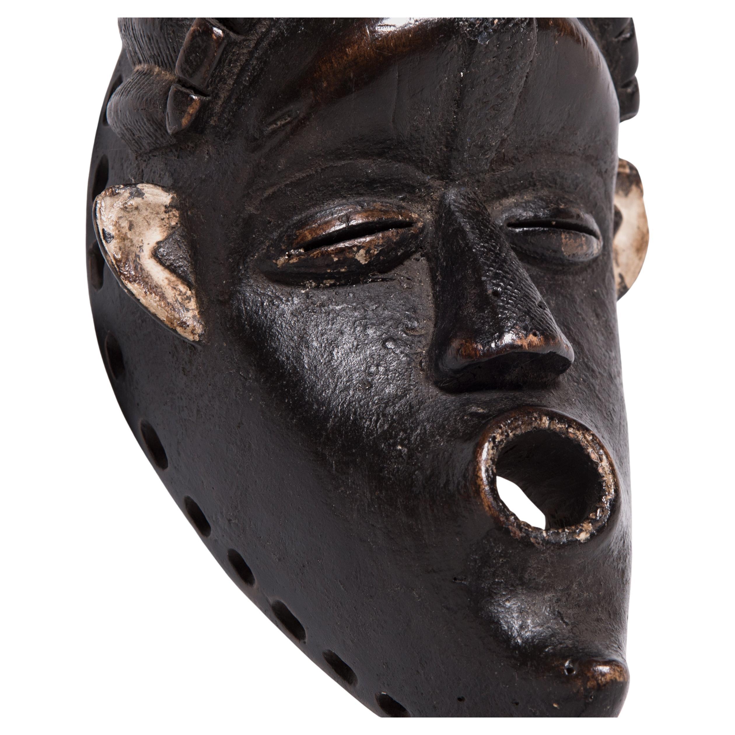 Diese mit einer außergewöhnlichen schwarzen Krustenpatina überzogene liberianische Holzmaske wurde im Stil der Bassa-Ethnie handgefertigt. Die Bassa-Gemeinschaften verfügen über eine Vielzahl von Maskentraditionen. Dazu gehören Chu-Den-Zo und No,