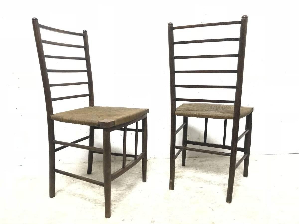 Liberty and Co, une paire de chaises latérales Arts & Crafts à dossier en échelle, avec les sièges d'origine finement disposés et les détails élégants et simples des montants à l'avant, unissant le brancard avant.
Je dispose également d'une version