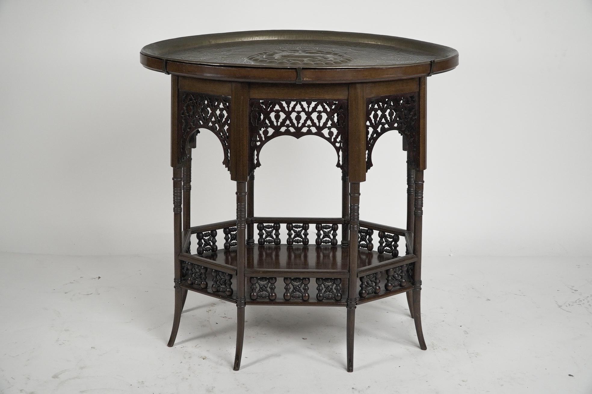 Liberty and Co. A rare and unusual Moorish oval eight leg side table with a brass removable top embossed with a medieval lioness holding a sword while her cub feeds from her. With eight arched fretwork panels running around the upper section the