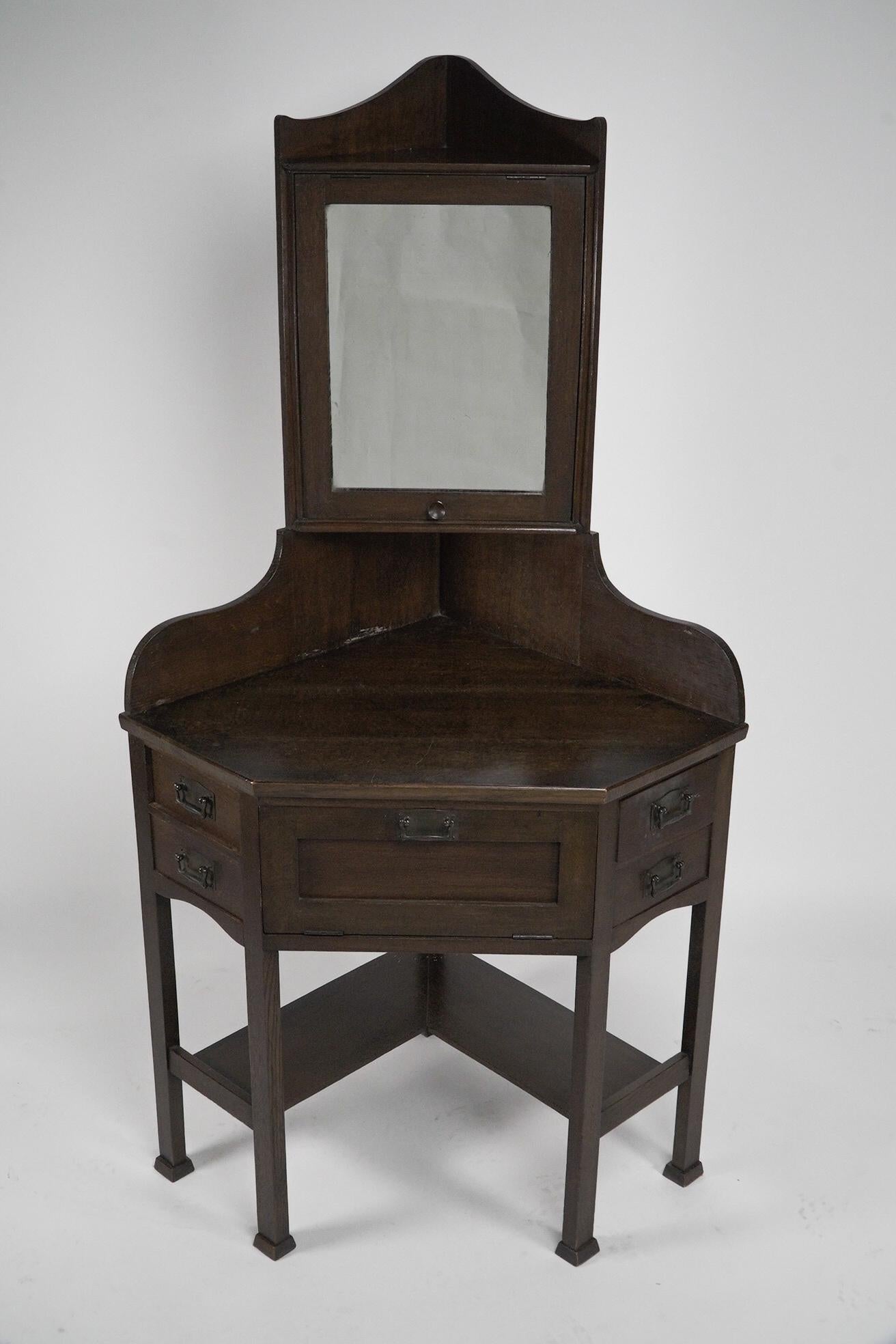 Liberty and Co. A rare and unusual Arts and Crafts oak corner dressing table. The mirror pulls up on a stop-and-stay system to adjust the angle. 
Illustrated in Liberty's Furniture 1875-1915. The Birth of Modern Interior Design. By Daryl Bennet.
