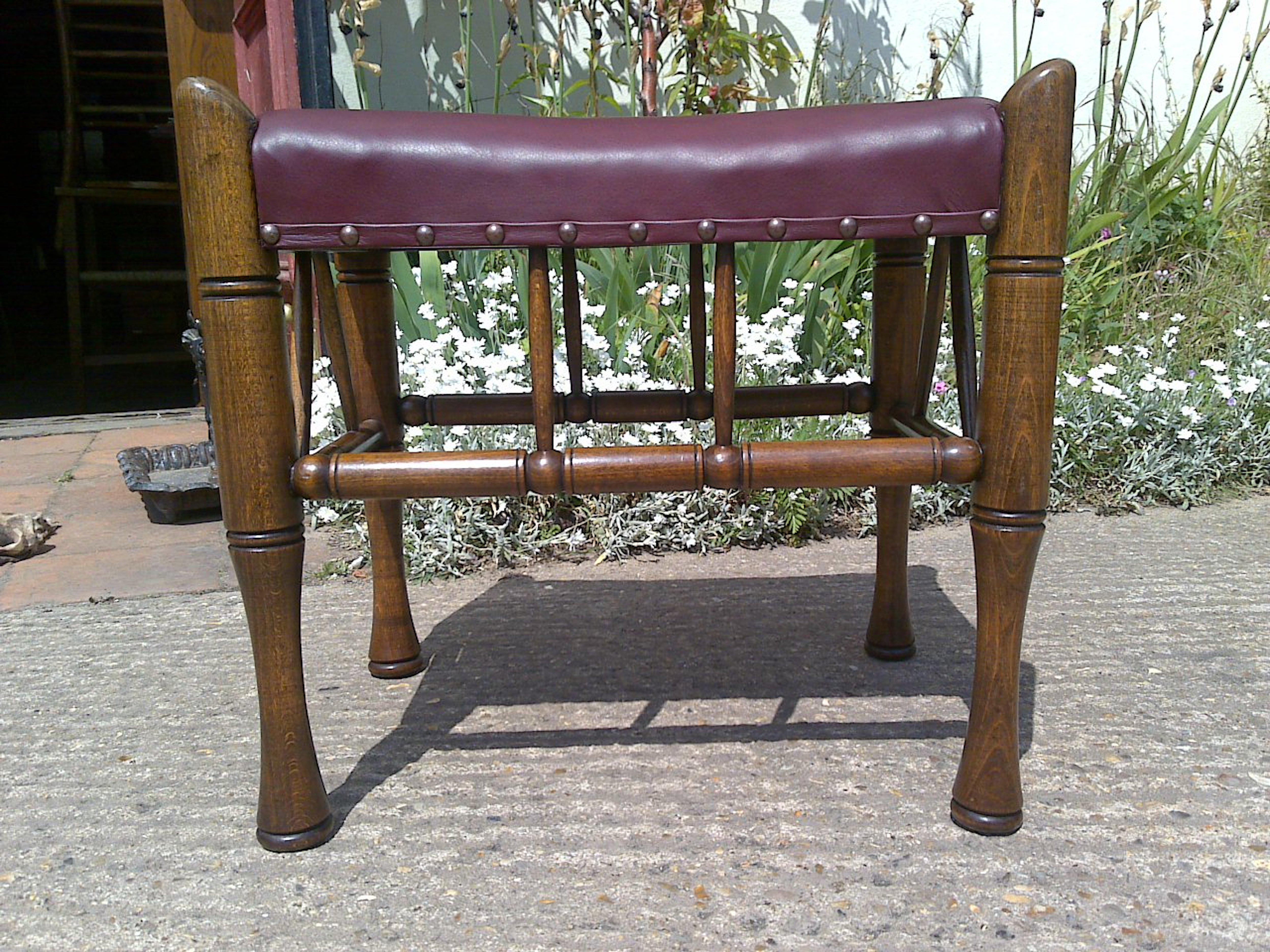 Liberty and Co. a stained beech Thebes stool, with a re upholstered red leather seat.