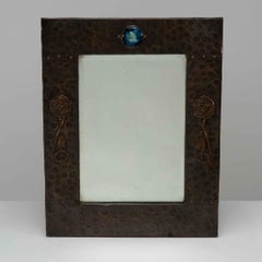 Liberty and Co. An Arts and Crafts copper mirror with a cloudy blue Ruskin Jewel