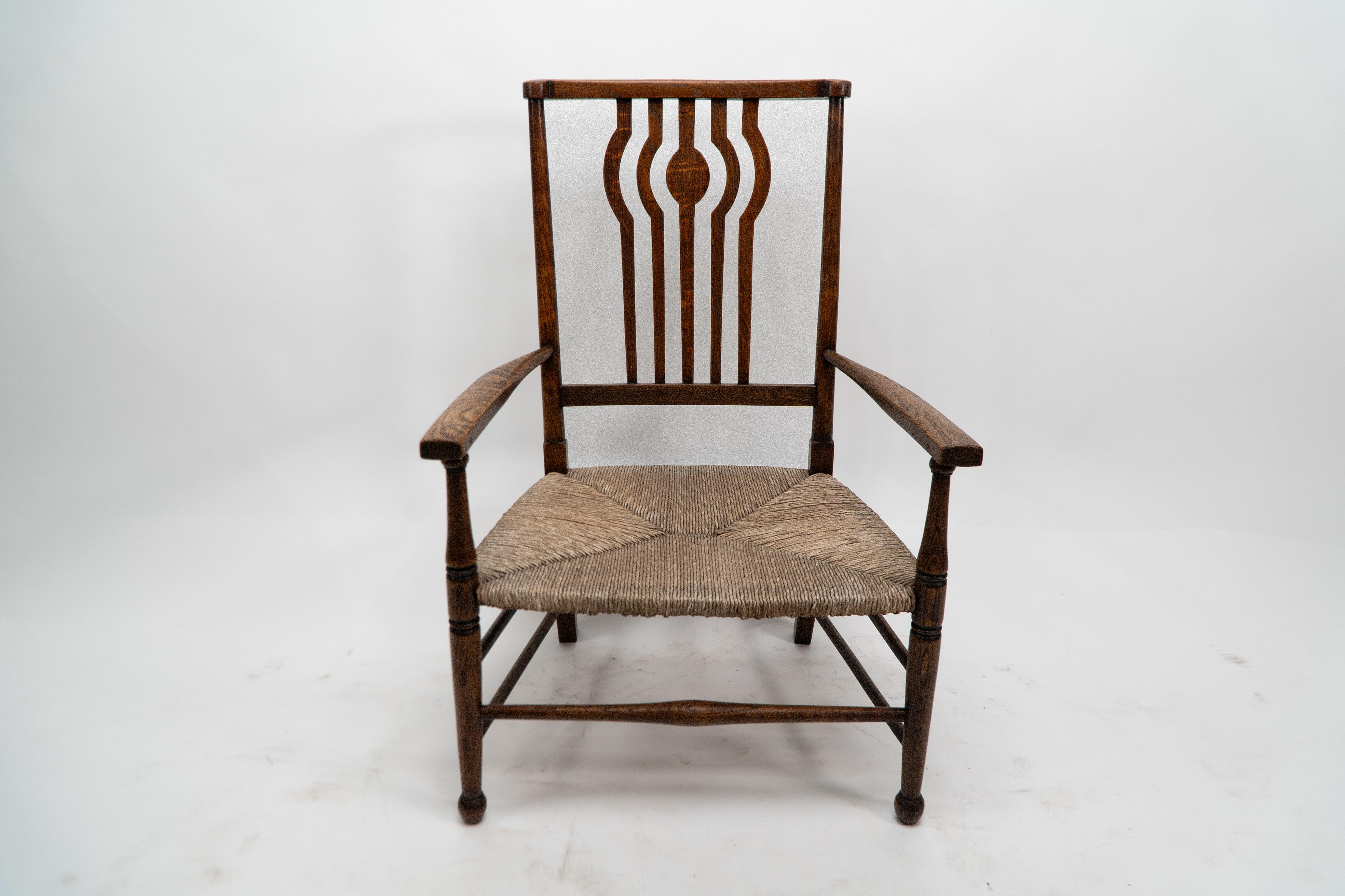 Liberty and Co. An Arts and Crafts rush seat armchair, with shaped back slats and stood on turned legs.
