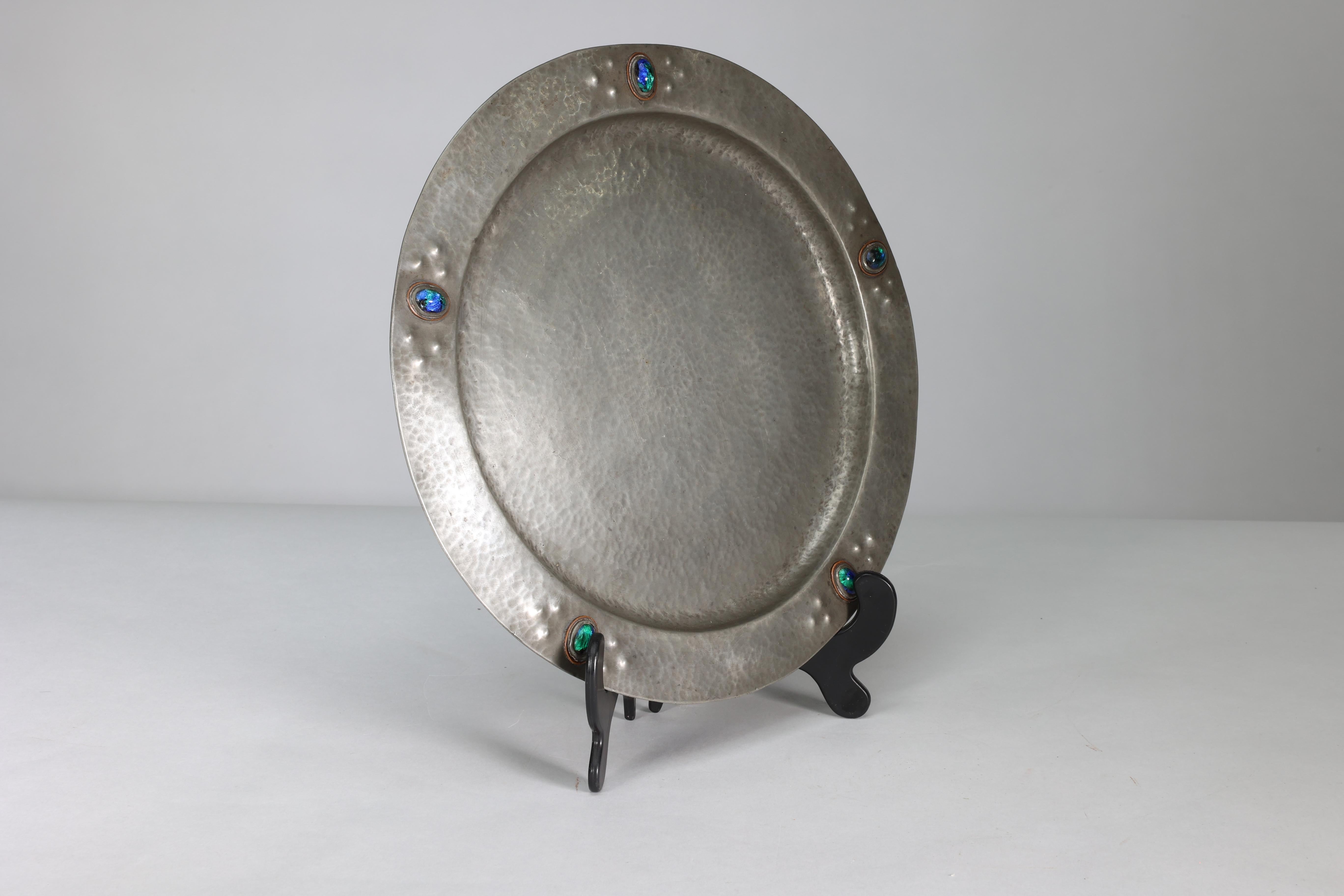 Liberty & Co attributed. An Arts & Crafts hand hammered pewter plate with five blue enamel jewels running around the edge.