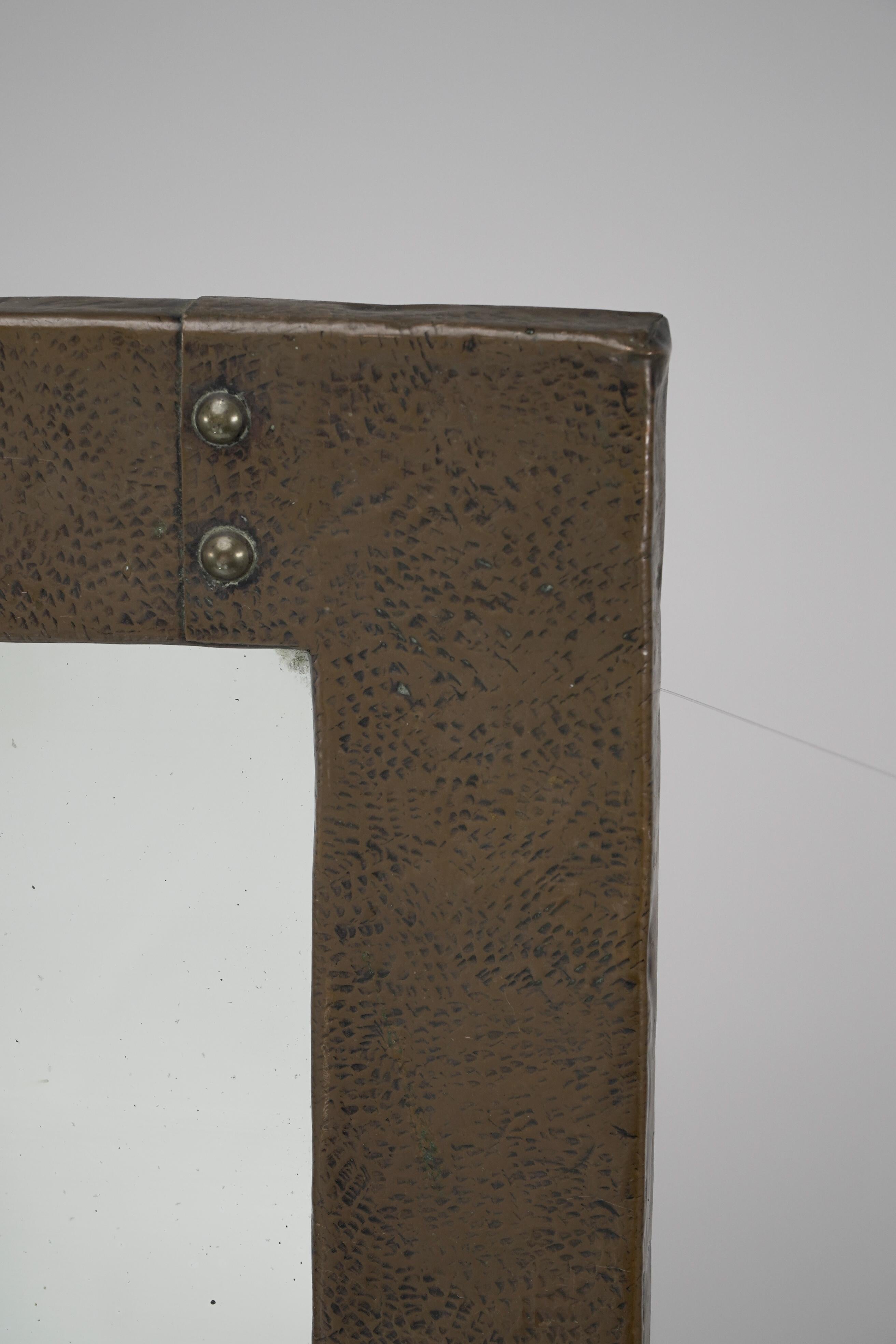 Liberty and Co. An Arts and Crafts copper mirror with a cloudy blue Ruskin Jewel to the top and Glasgow rose decoration to each side.