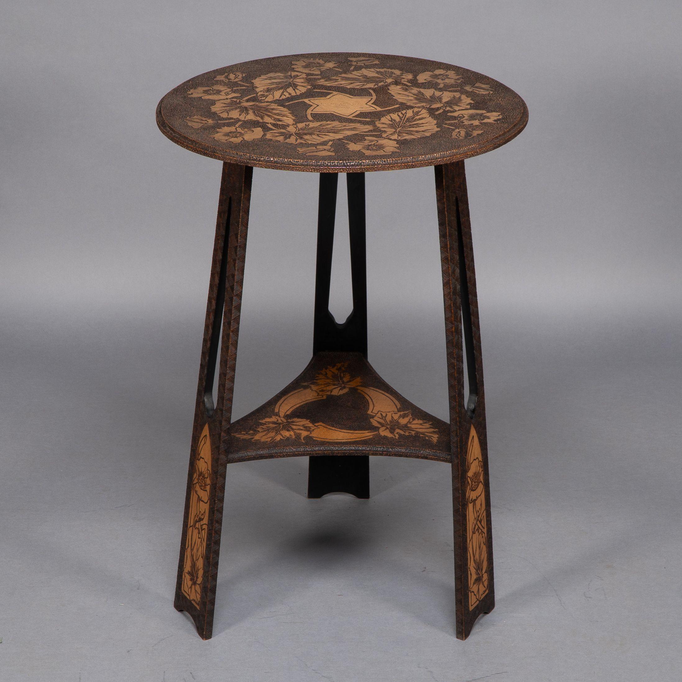 An intricately carved Arts and Crafts sidetable attribured to Liberty and Co with a stylised star and floral carvings to the circular top and to the three pierced legs all united by a lower triangular shelf.