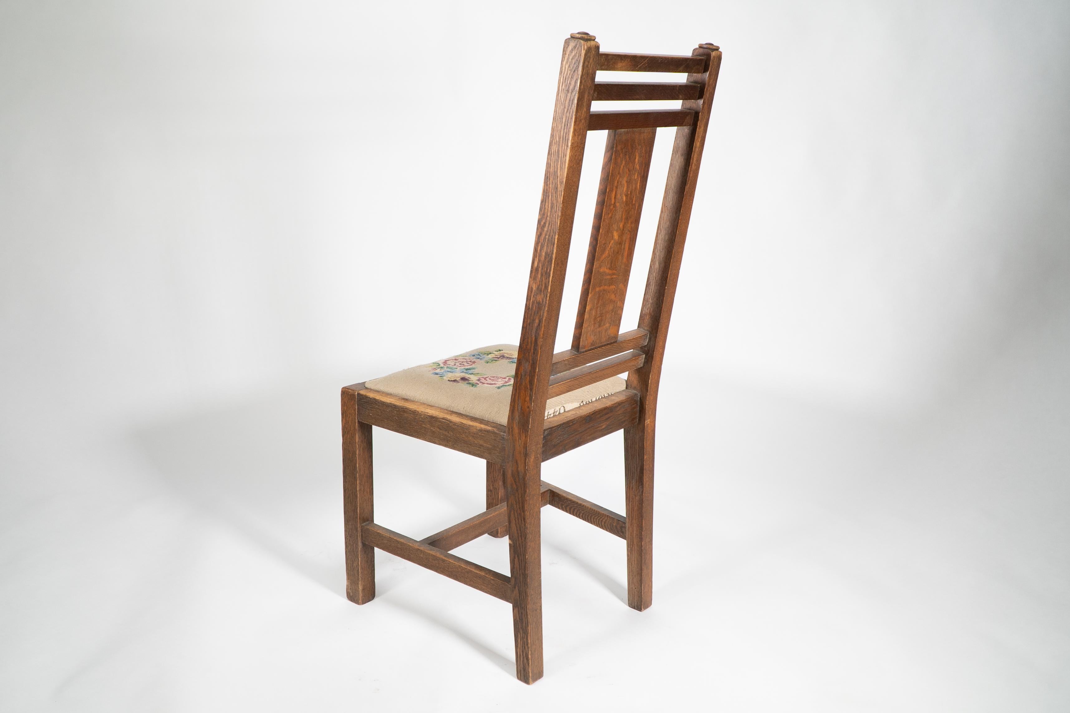 Early 20th Century Liberty & Co. An Arts & Crafts oak chair with carved rose decoration to the back For Sale