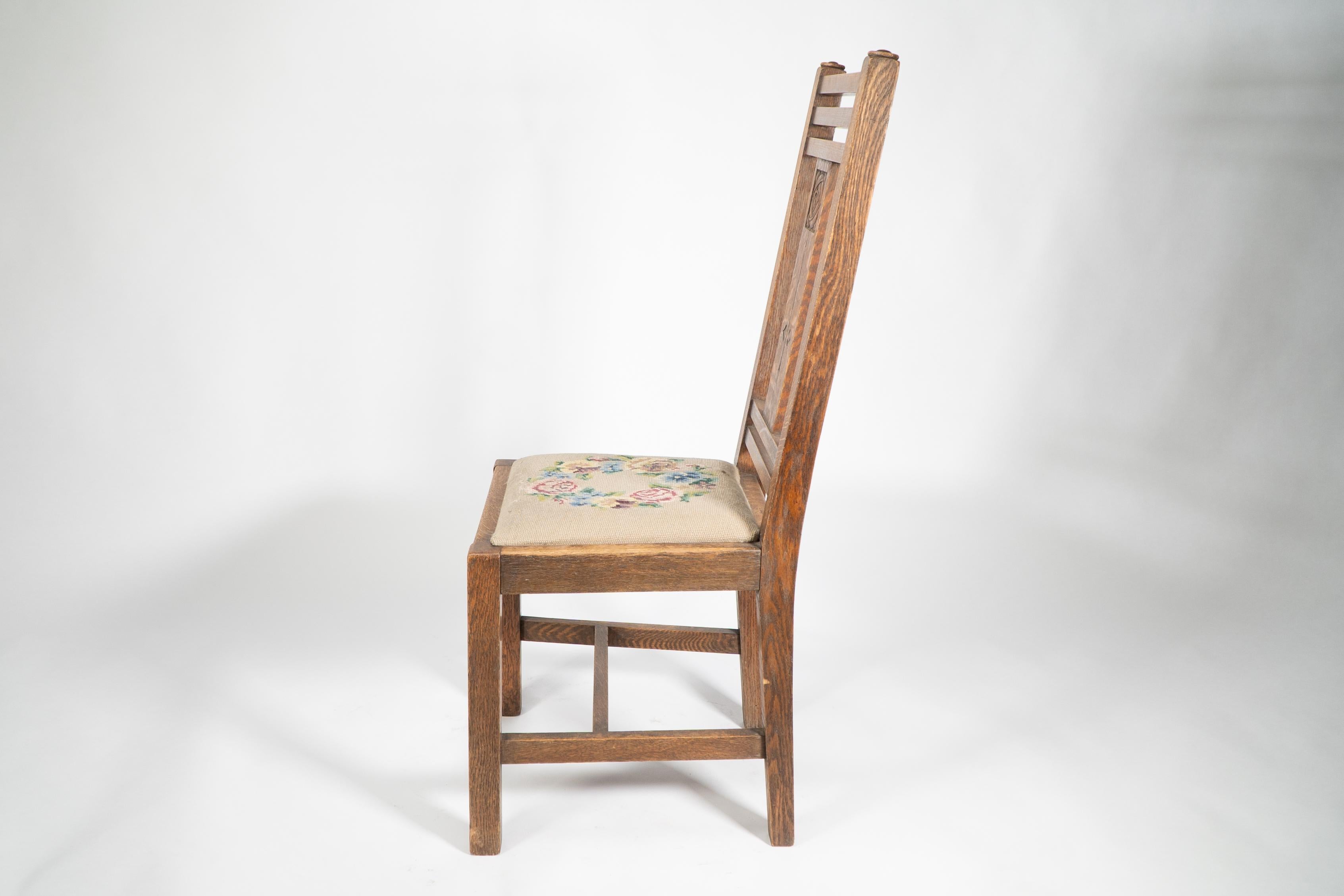 English Liberty & Co. An Arts & Crafts oak chair with carved rose decoration to the back For Sale