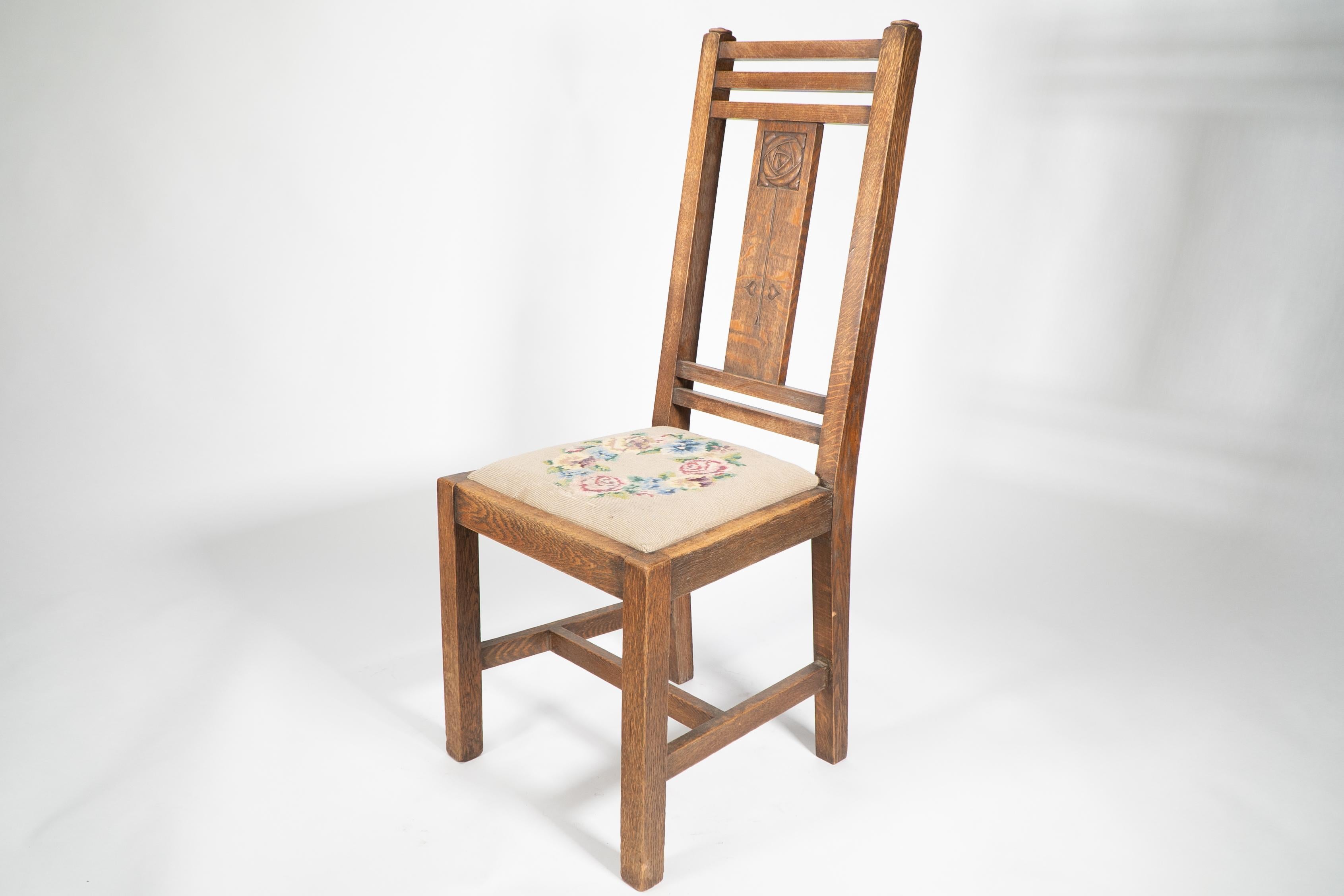 Arts and Crafts Liberty & Co. An Arts & Crafts oak chair with carved rose decoration to the back For Sale