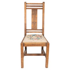 Liberty and Co. An oak chair with carved rose decoration to the back.