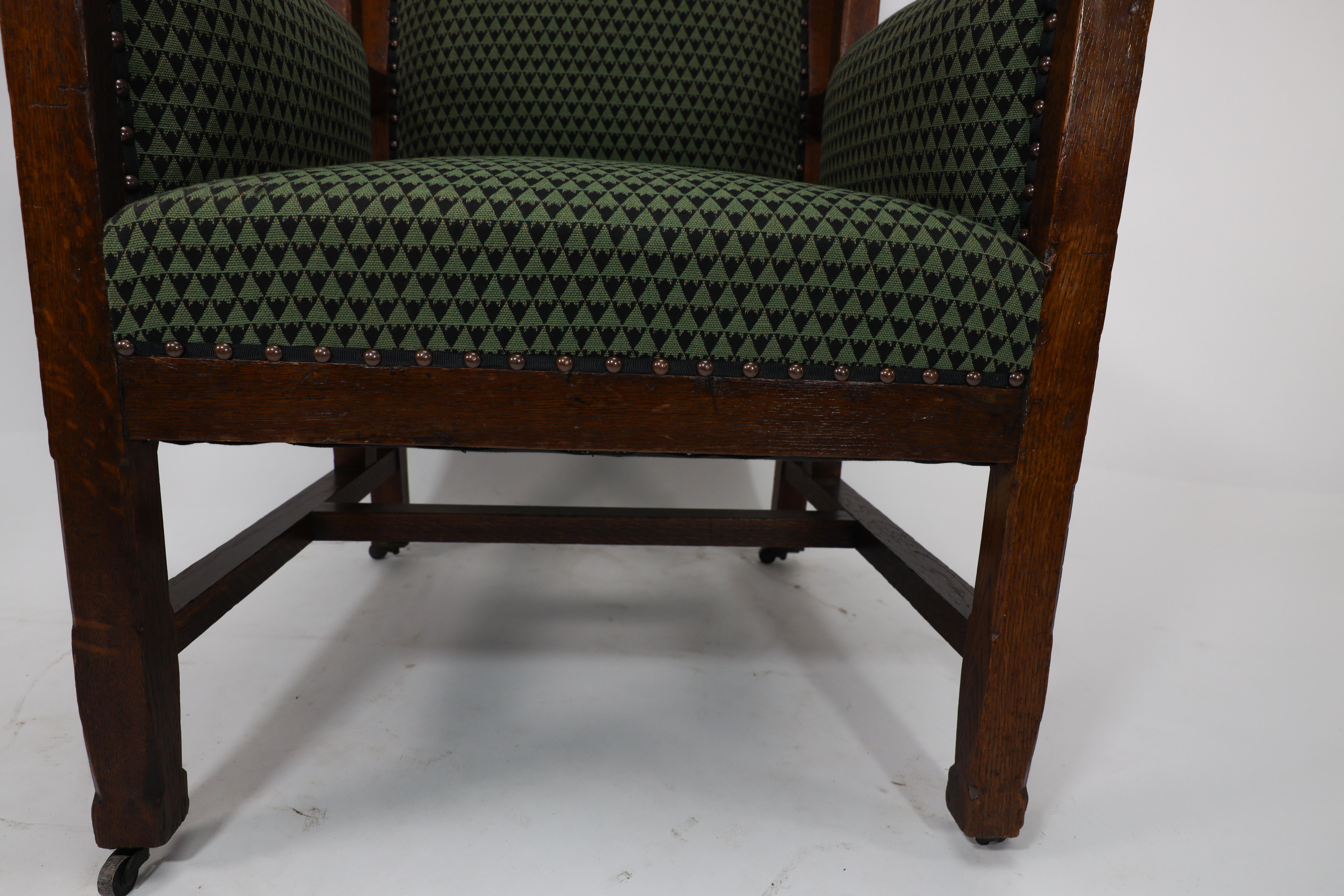 Liberty and Co, attr. in the style of Leonard Wyburd. An oak wing back armchair For Sale 7