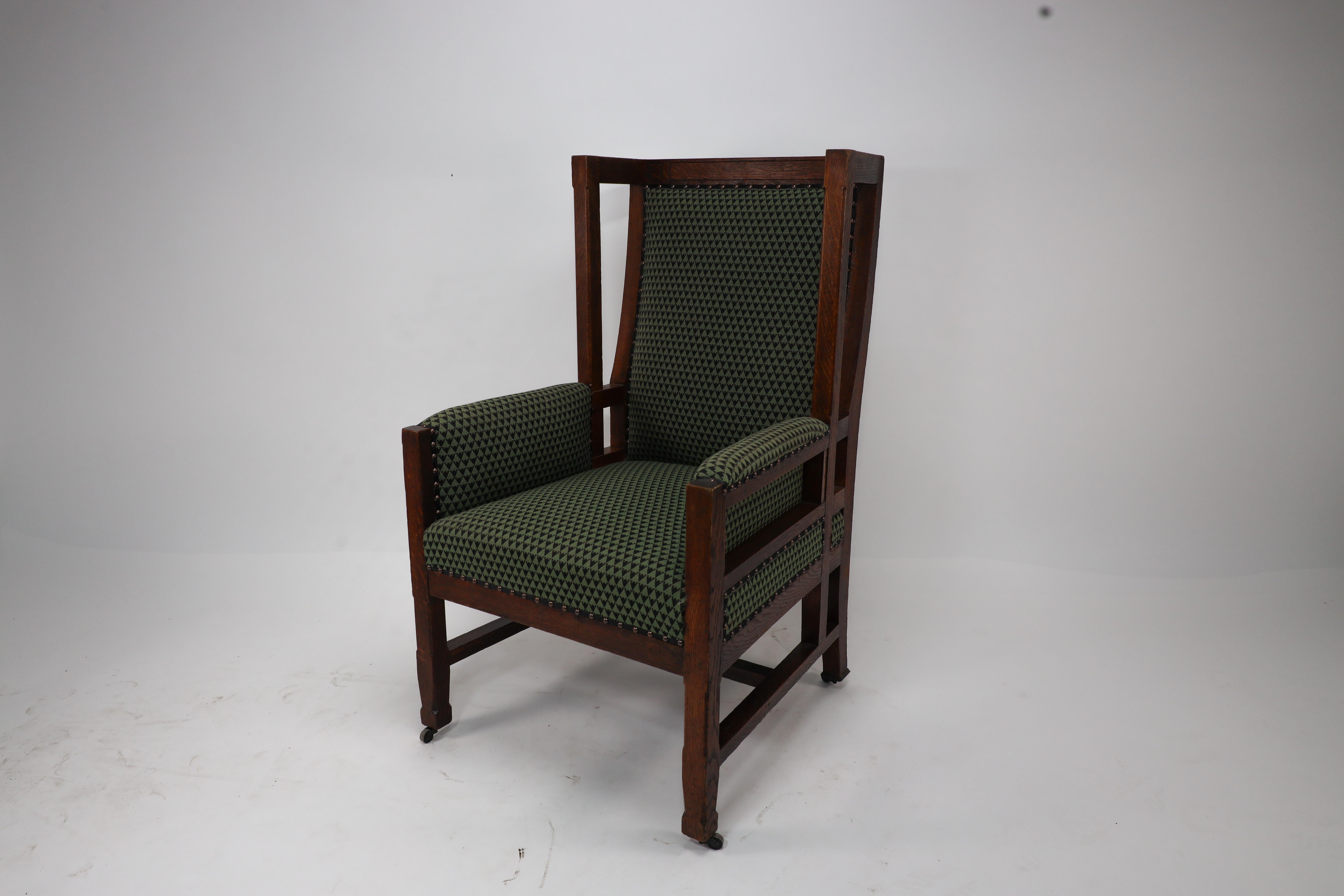 Arts and Crafts Liberty and Co, attr. in the style of Leonard Wyburd. An oak wing back armchair For Sale