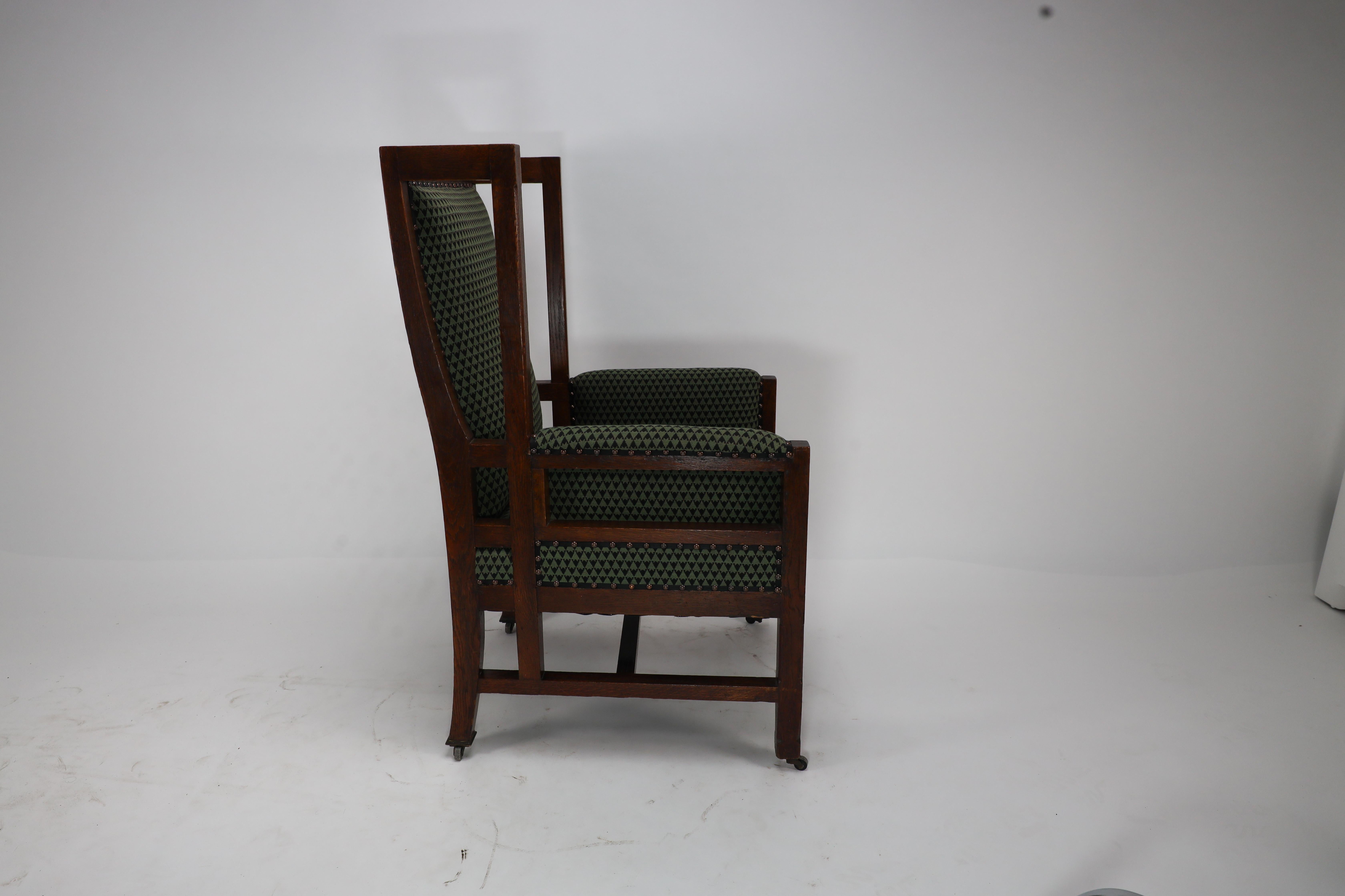 Oak Liberty and Co, attr. in the style of Leonard Wyburd. An oak wing back armchair For Sale