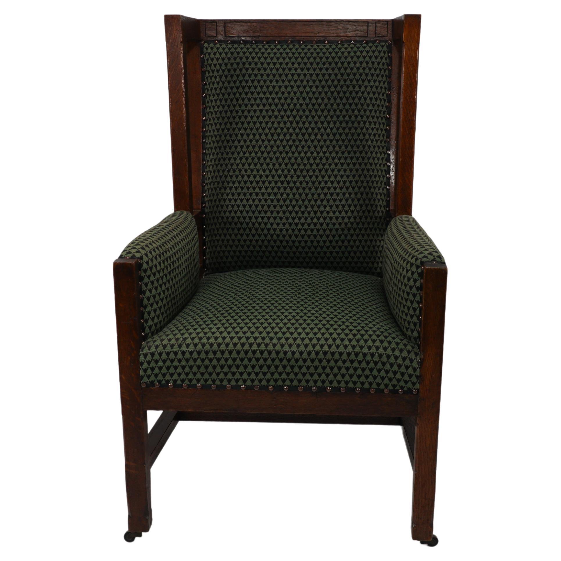 Liberty and Co, attributed, in the style of Leonard Wyburd. An Arts and Crafts oak wing back armchair with unusual upper open sides. The back supports curve down through to the back legs. The forward part of the wings follow down through the arms