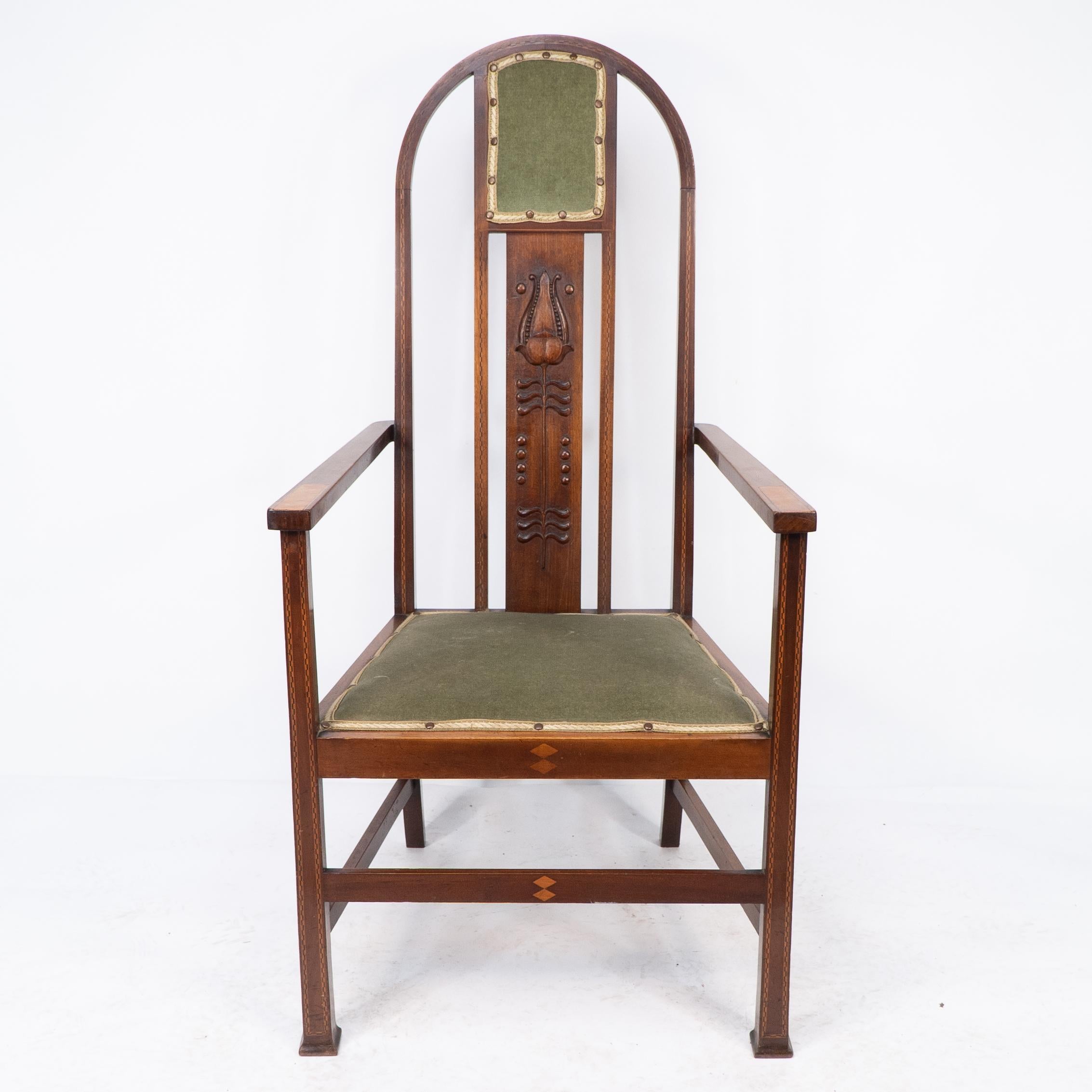 Liberty and Co attri, An Arts and Crafts mahogany armchair, with carved stylized plant motif to the central splat flanked by chequered ebony and boxwood stringing and inlaid walnut strips to the arms with double diamond inlay to the front seat rail