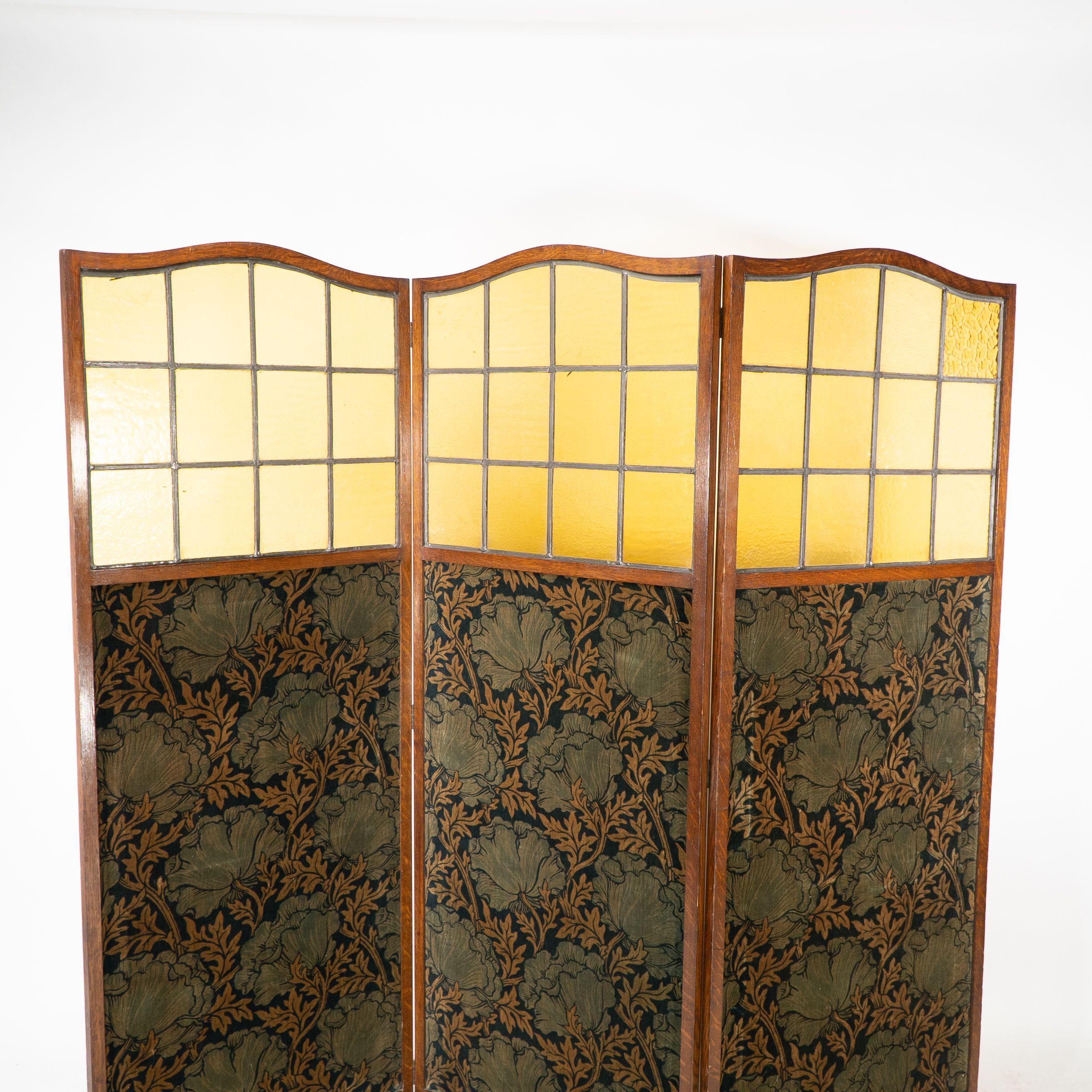 A good three fold screen attributed to Liberty and Co with arched tops, amber glass and original fabric attributed to The Silver Studio's. Each section is 24