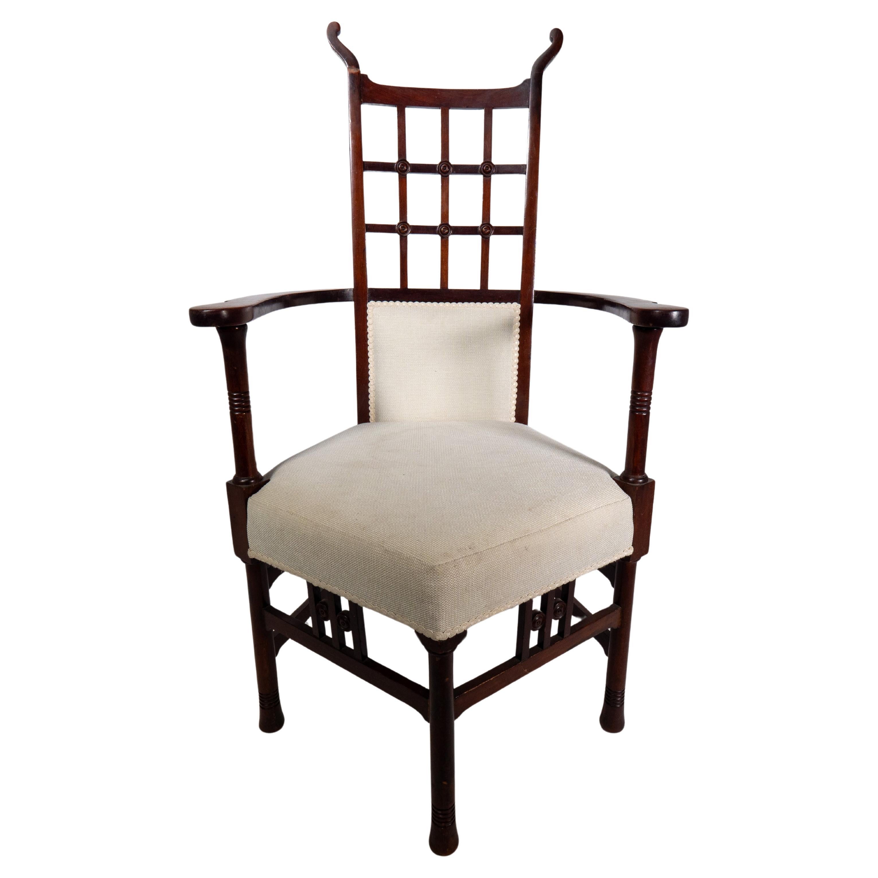 Liberty and Co in the style of probably made by William Birch. 
An Arts and Crafts mahogany armchair with curled finials, and a lattice back support ring turned details to the arm supports and also to the five legs.
