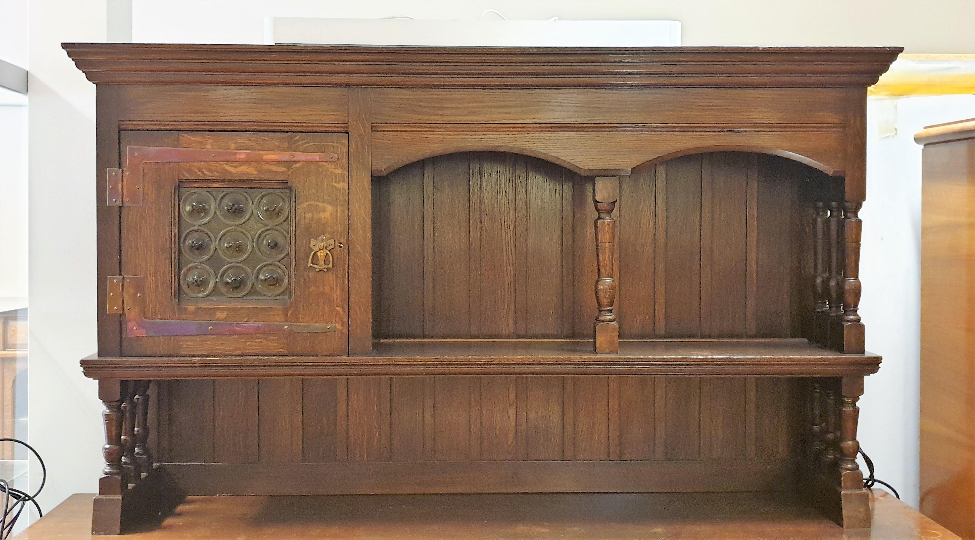 A fine Liberty & Co. ‘Lochleven’ Arts & Crafts oak sideboard, featuring leaded glass to upper cupboard door and metal strap work hinges

The ‘Lochleven’ sideboard first appeared the Liberty & Co., handbook of sketches, 1889 and remained popular