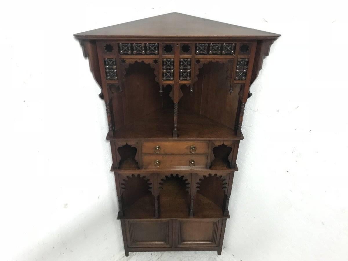 Liberty & Co. A Moorish style walnut corner cupboard with Musharabieh turnings and fretwork details to the upper section with twin central drawers with brass ring pull handles and a cupboard to the base.
Stamped to the back. Liberty & Co 0,