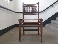 Liberty & Co. Una poltrona moresca in noce con sedile in pelle a spiovente in stile tebano