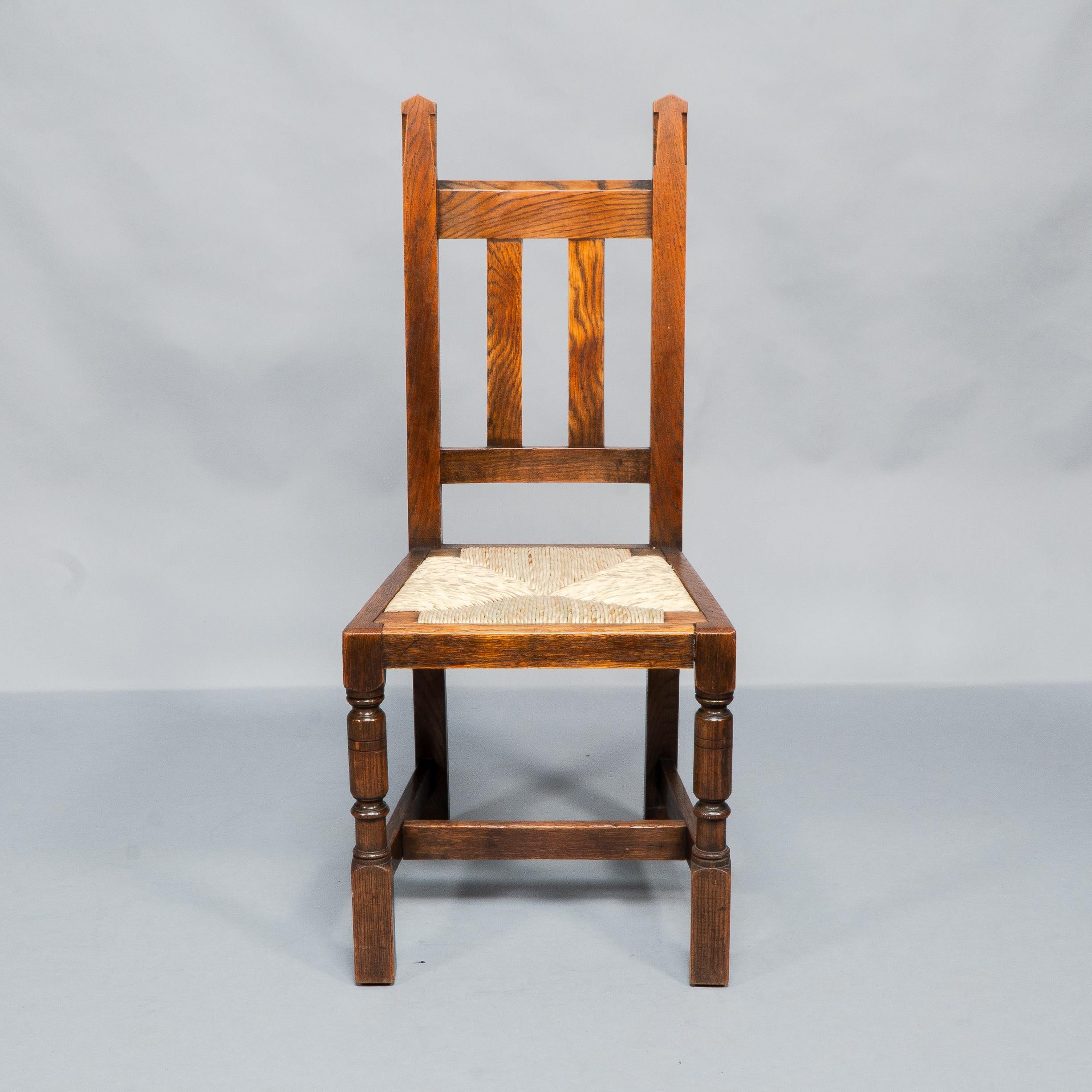 Liberty & Co. A Set of Six Arts & Crafts Oak Arrowhead Rush Seat Dining Chairs. In Good Condition For Sale In London, GB