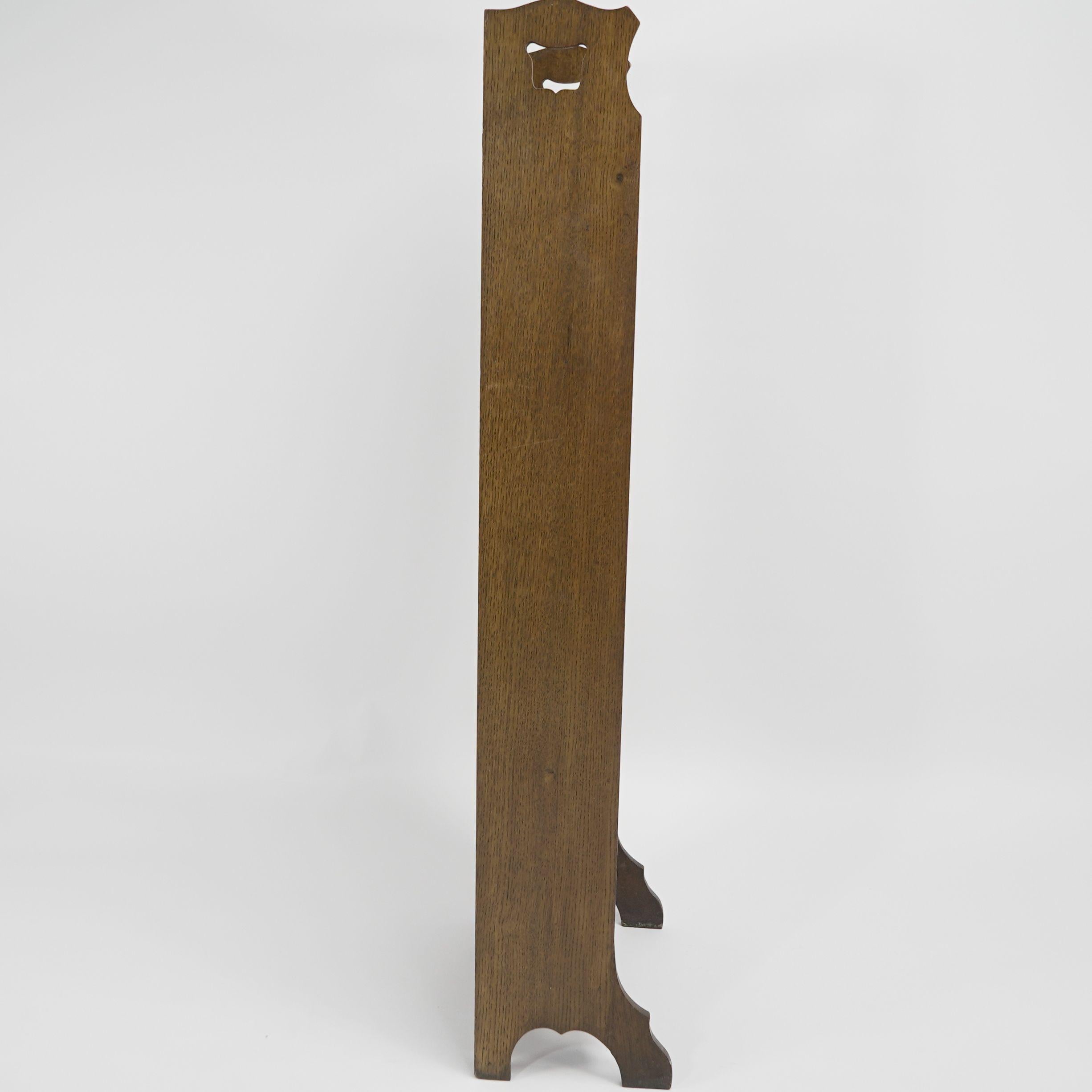 Liberty and Co. A slim Arts and Crafts oak bookcase with stylized floral cut-outs to the upper back and Tulip style cut-outs to the sides.