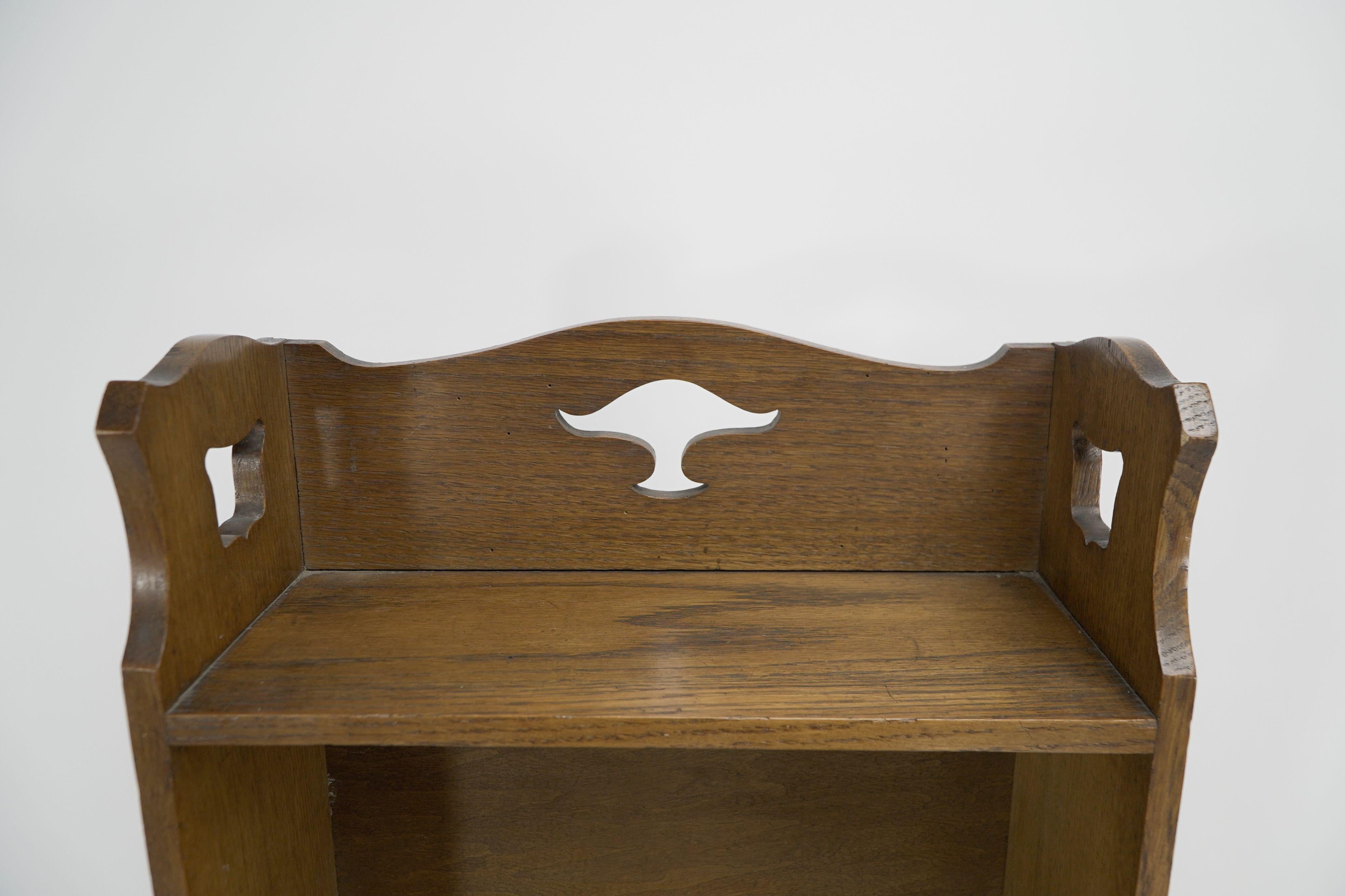 English Liberty & Co. A slim Arts and Crafts oak bookcase with stylized floral cut-outs For Sale